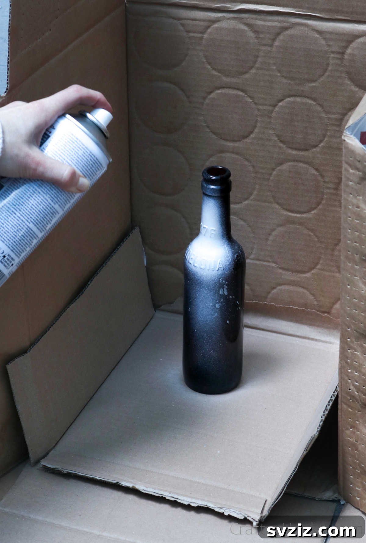 Person spray painting a beer bottle white