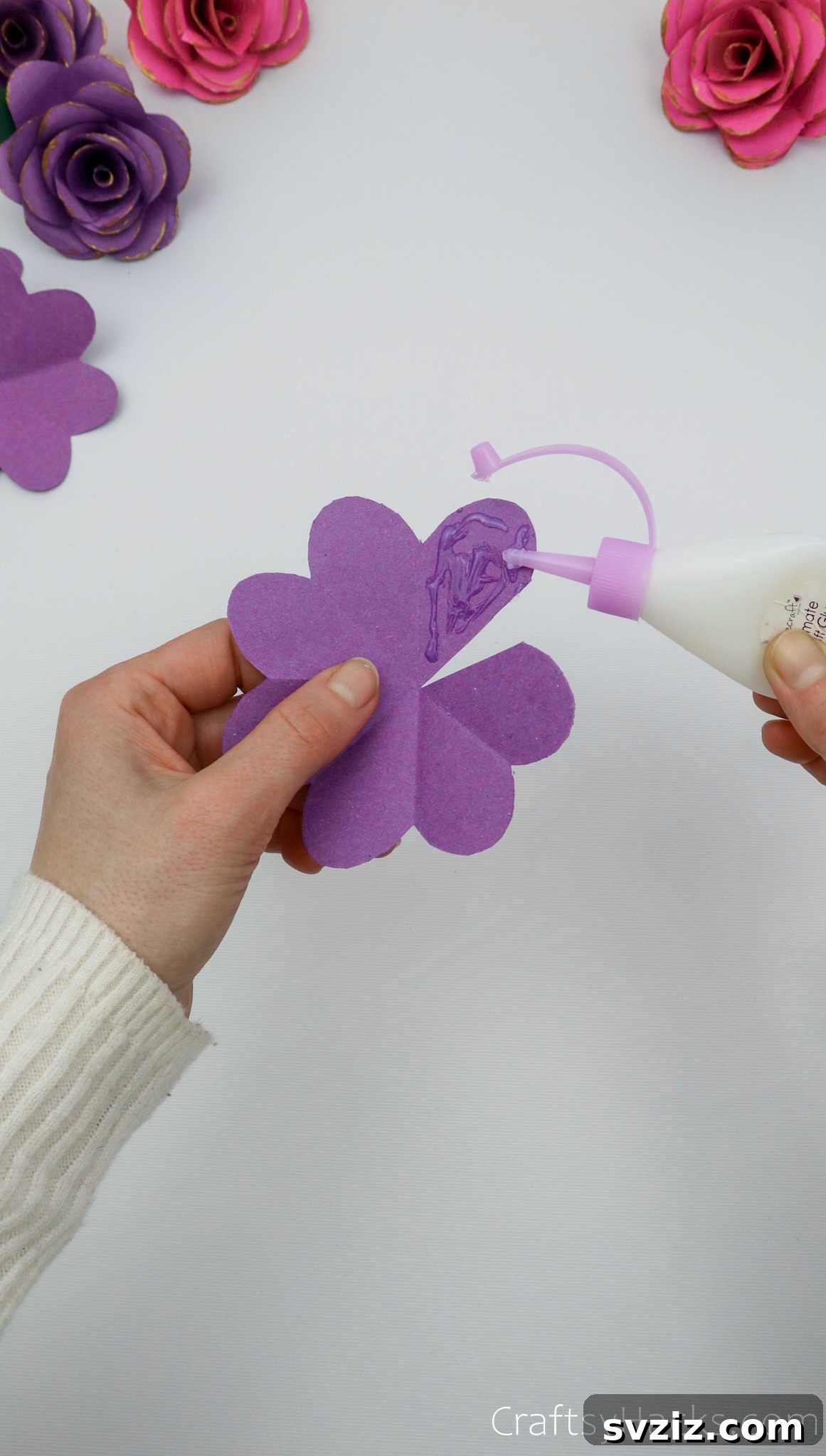 Crafting Beautiful Paper Blooms 17 A hand applying craft glue to the edge of a paper petal, preparing to overlap it
