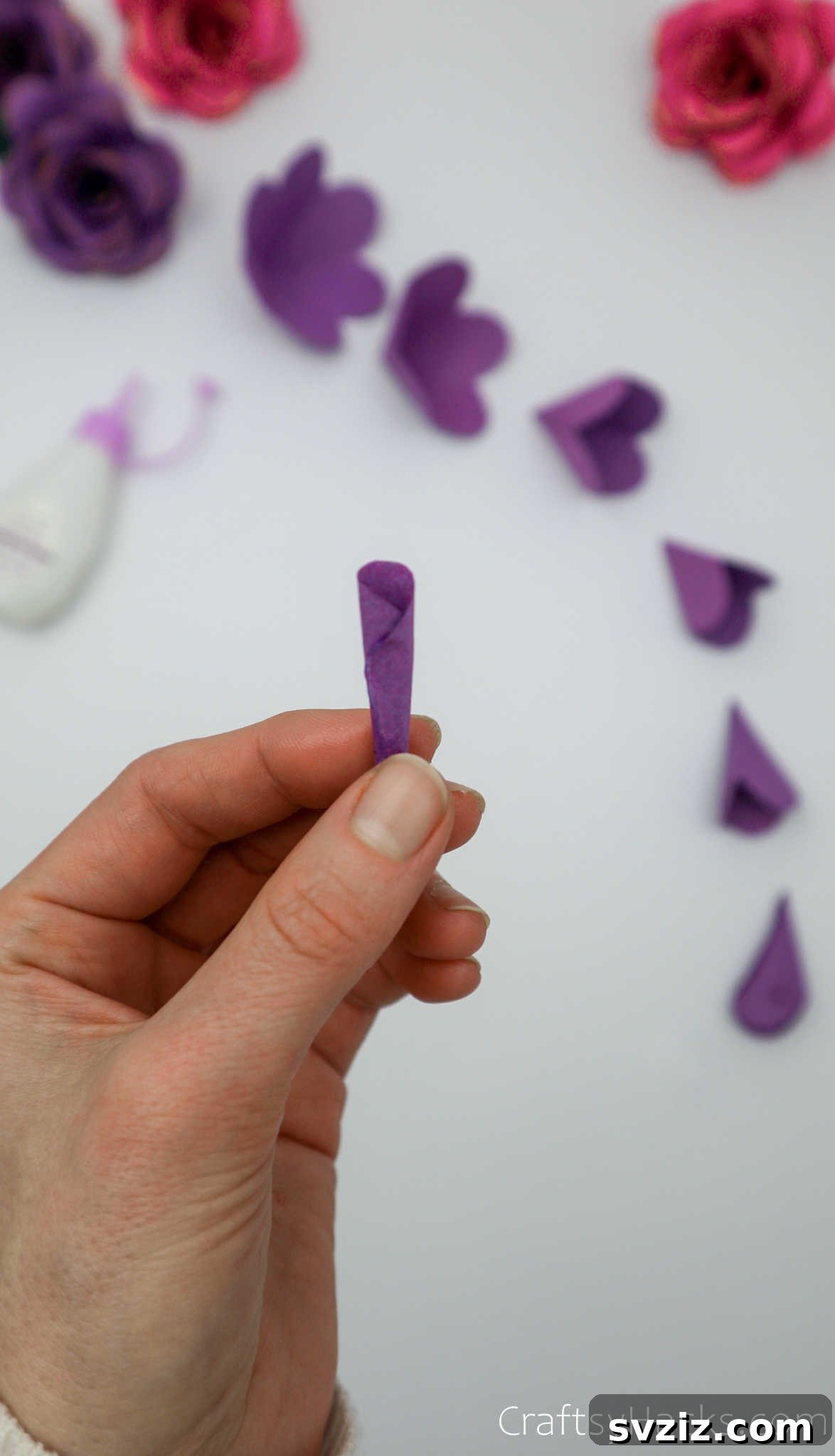 Crafting Beautiful Paper Blooms 21 A small purple paper petal tightly rolled into a cone shape, forming the flower's center