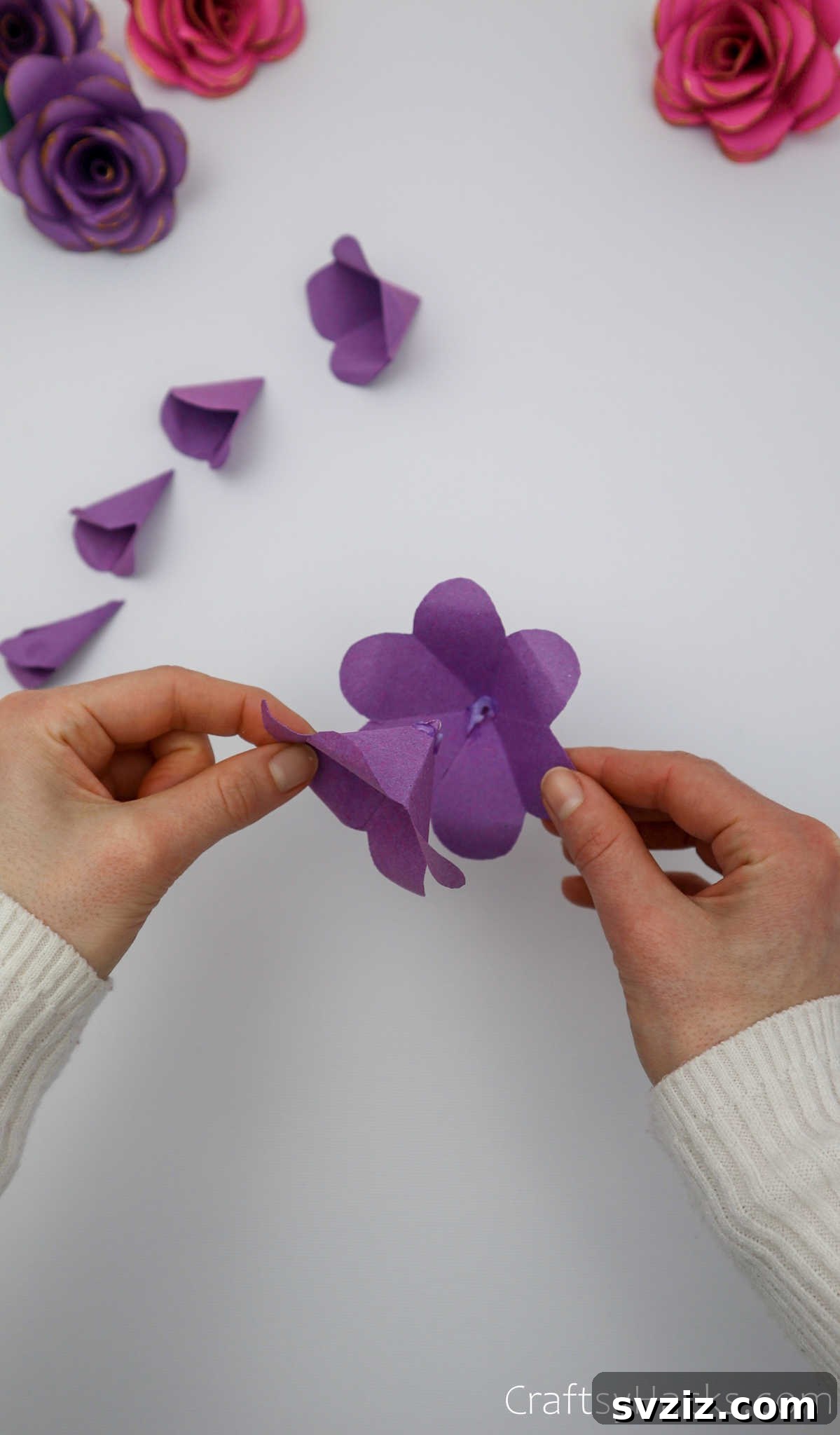Crafting Beautiful Paper Blooms 24 A hand carefully gluing and assembling paper flower layers together, building the bloom