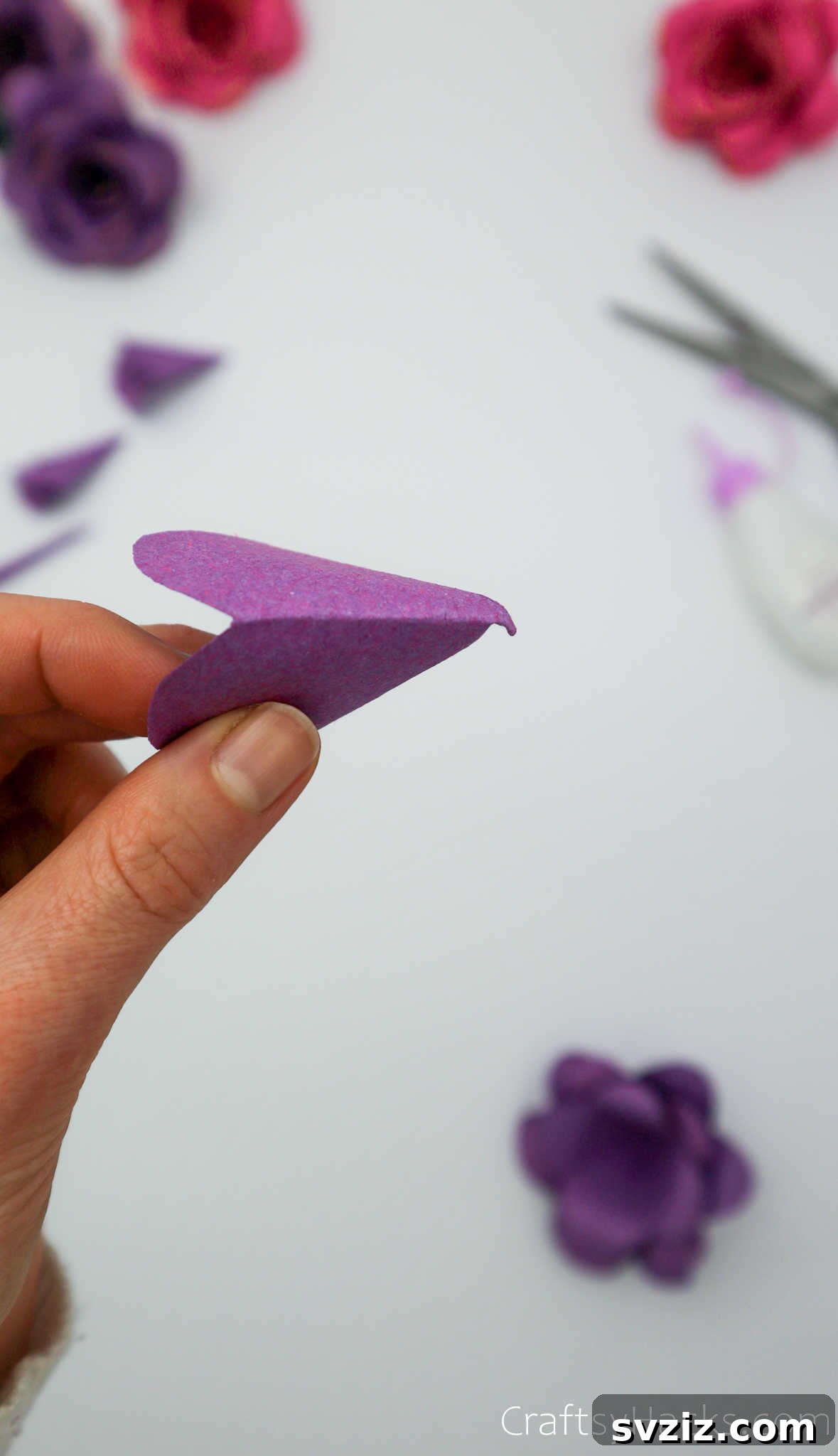 Crafting Beautiful Paper Blooms 26 A hand gently pressing the final, smallest paper petal layer into the center of the flower