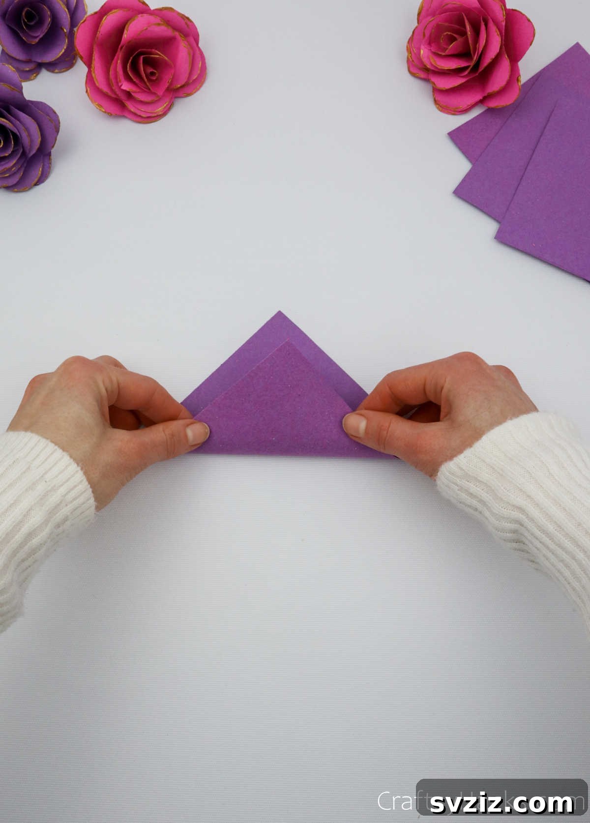 Crafting Beautiful Paper Blooms 6 A hand precisely folding a purple paper square diagonally to form a triangle