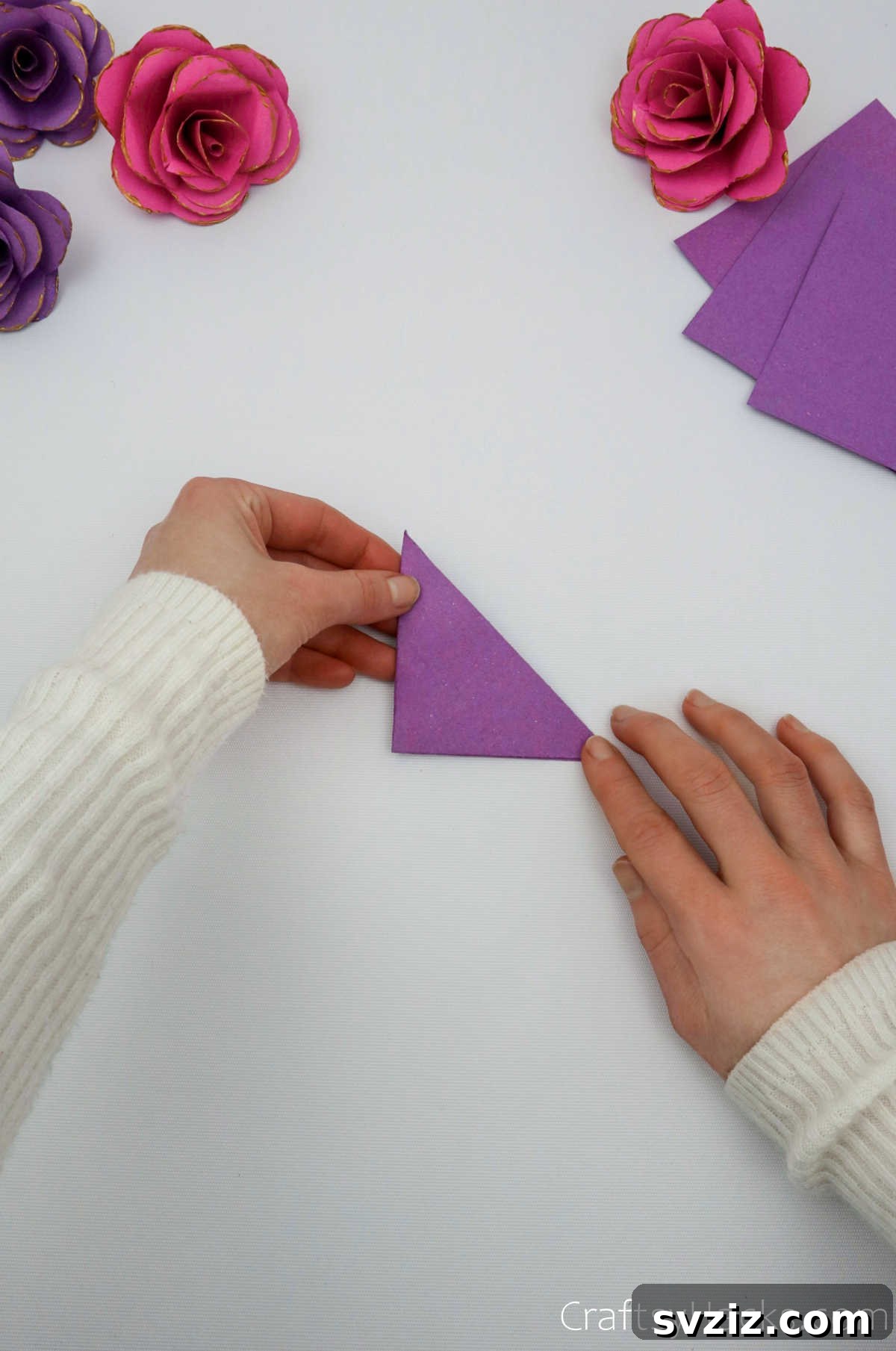 Crafting Beautiful Paper Blooms 8 A hand performing the second diagonal fold on a paper triangle to create a smaller triangle