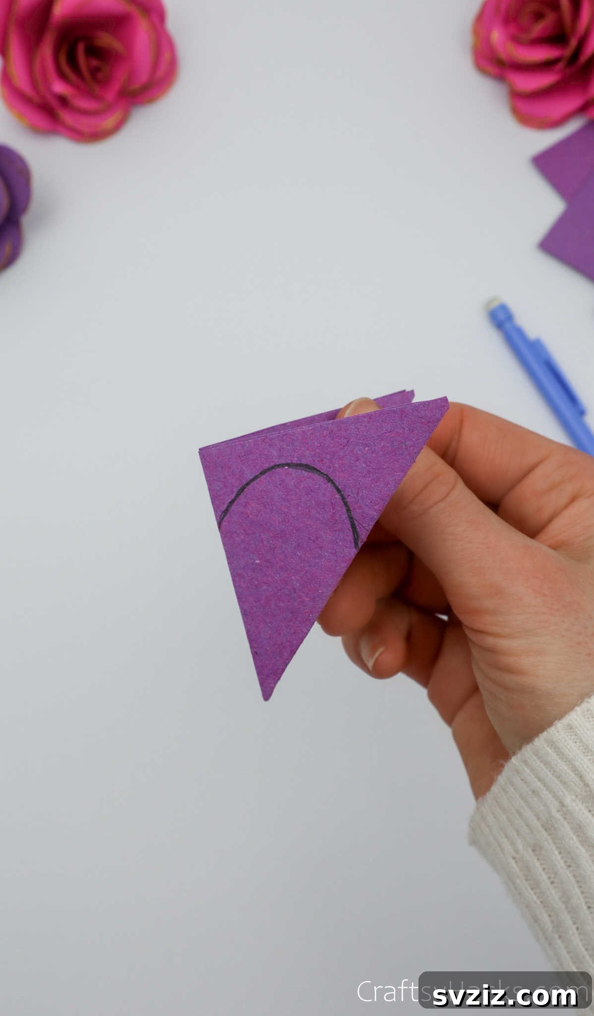 Crafting Beautiful Paper Blooms 10 A pencil drawing a curved arc on the folded paper triangle, outlining the petal shape