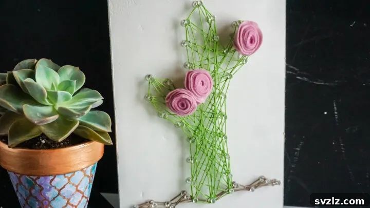 Creating cactus string art on wood with colorful threads.