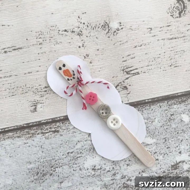 Rustic snowman decoration made from a popsicle stick.