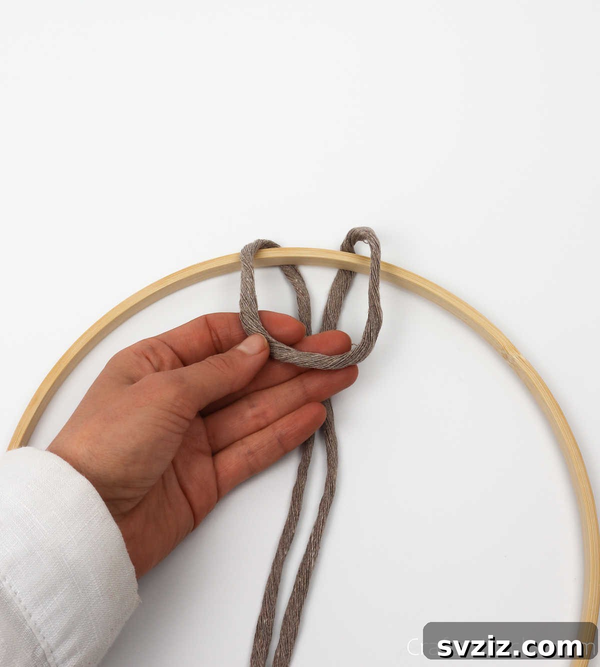 The process of looping the folded cord over the hoop, forming the initial shape of the knot.