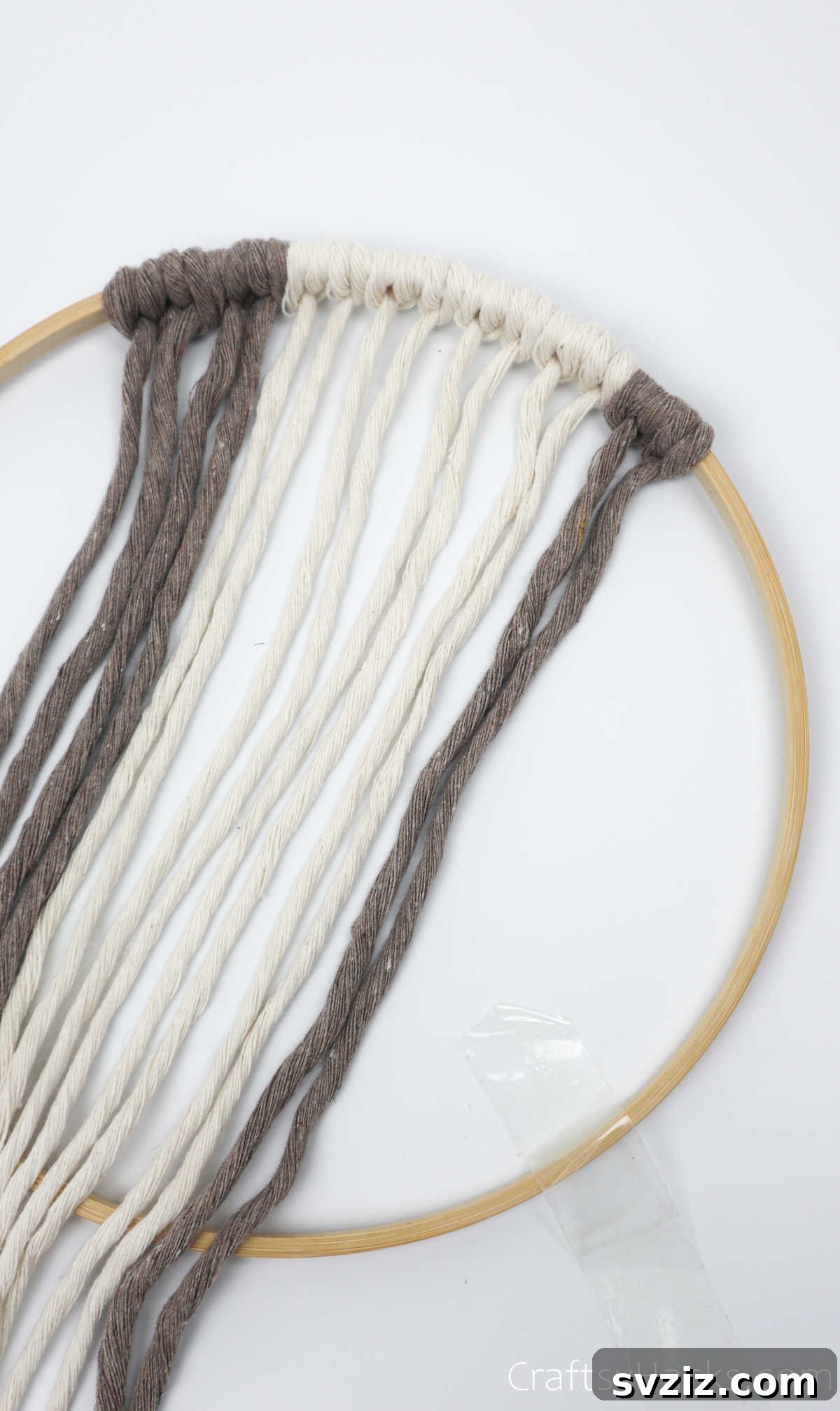 Adding the final two cappuccino-colored cords to complete the pattern on one side of the hoop.