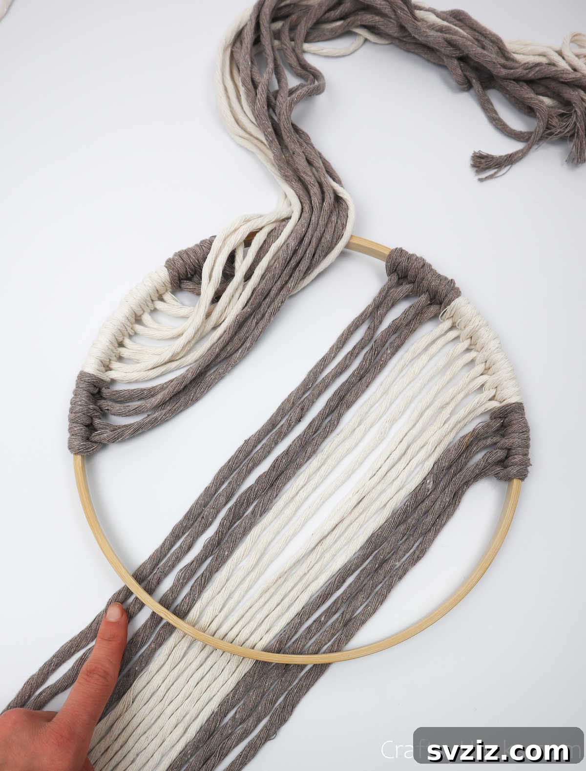 The left side of the yarn is lifted and gathered, clearing the workspace for the right side of the hoop.