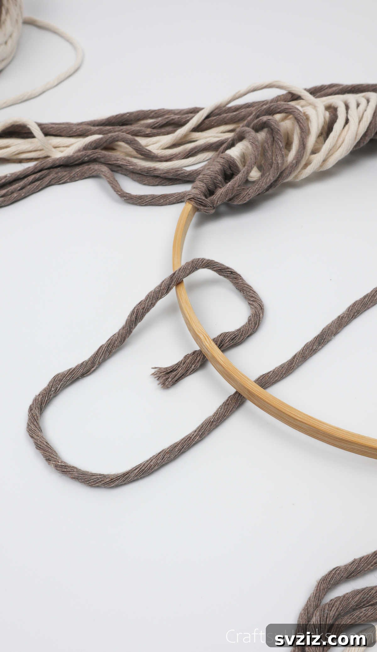 Pulling the first cappuccino cord over and under the hoop to form a diagonal loop for knotting.