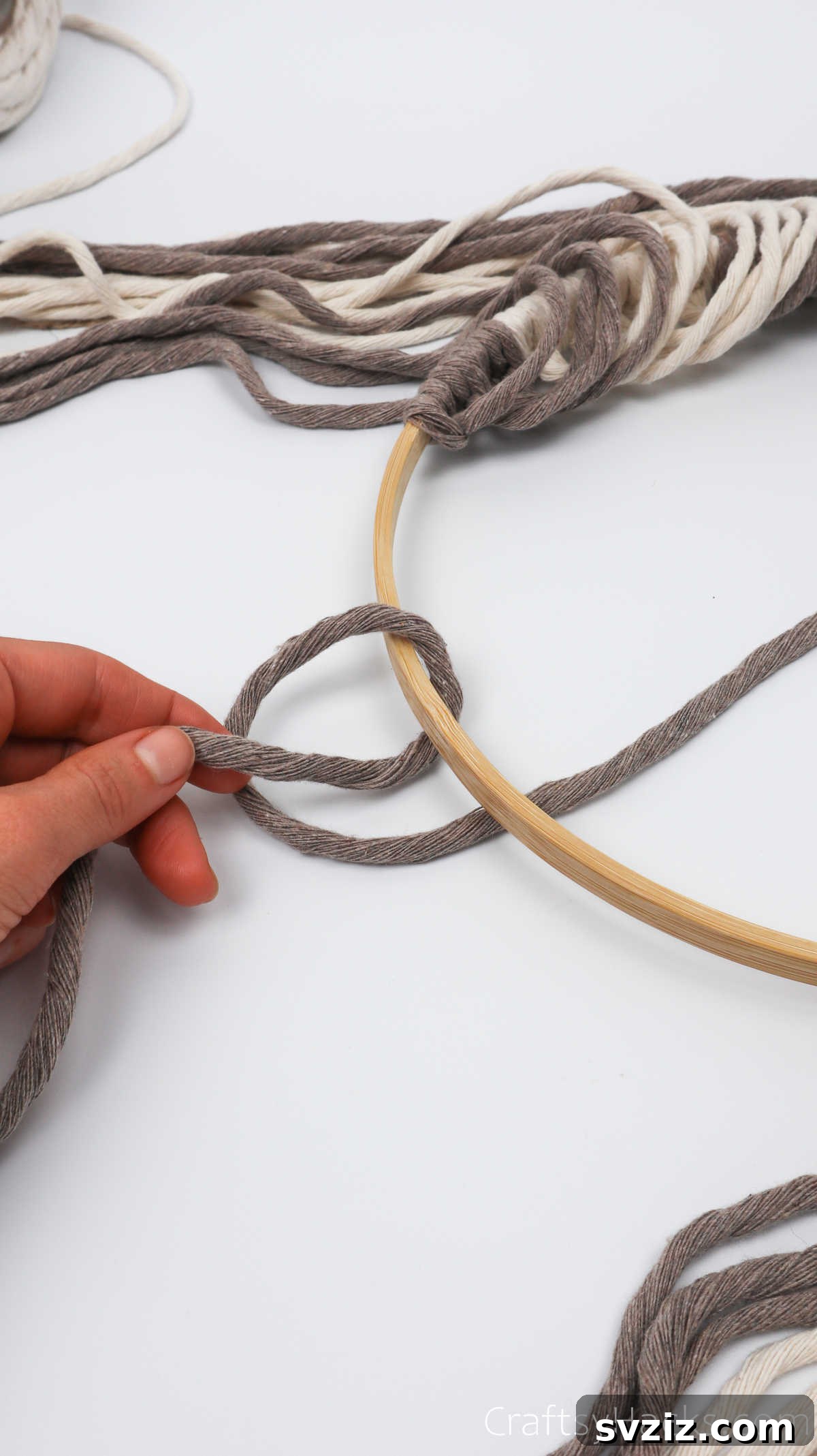 The initial step of folding yarn around the hoop to create a half-knot for the diagonal pattern.