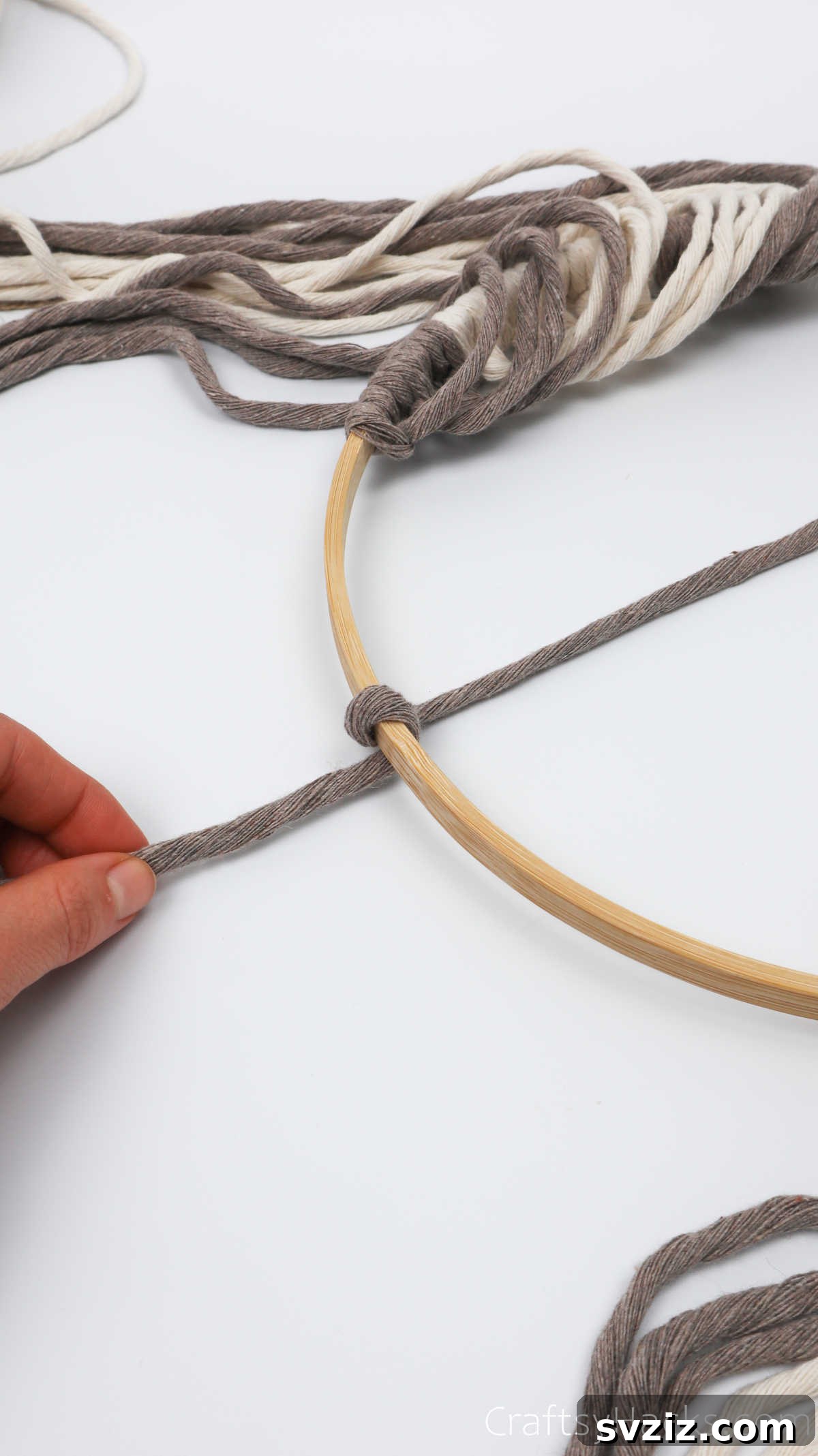 The process of looping the yarn securely around the hoop to form the half-knot.