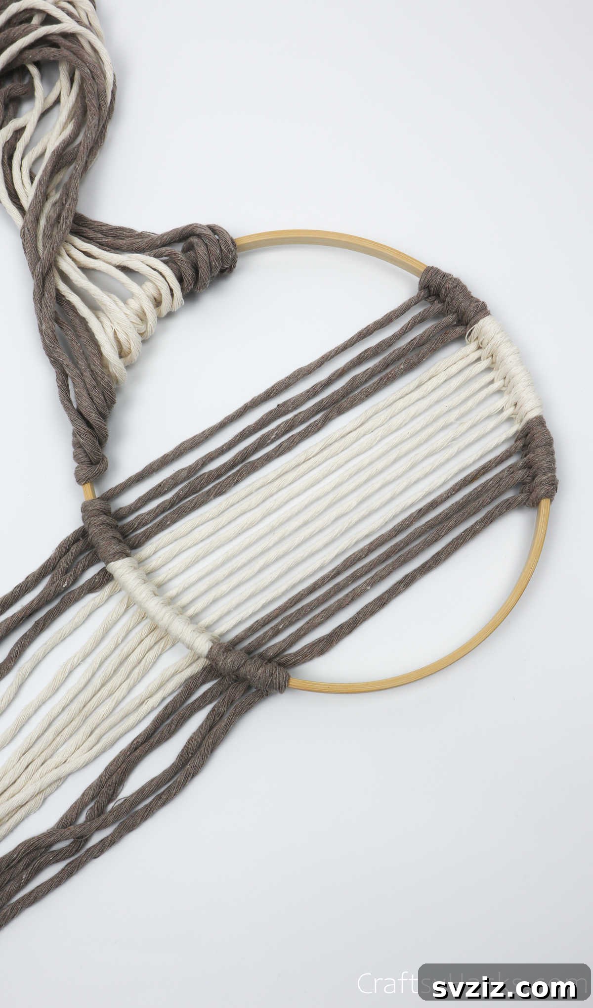One side of the knotted diagonal yarn is folded up, revealing the next section of the hoop to be worked on.