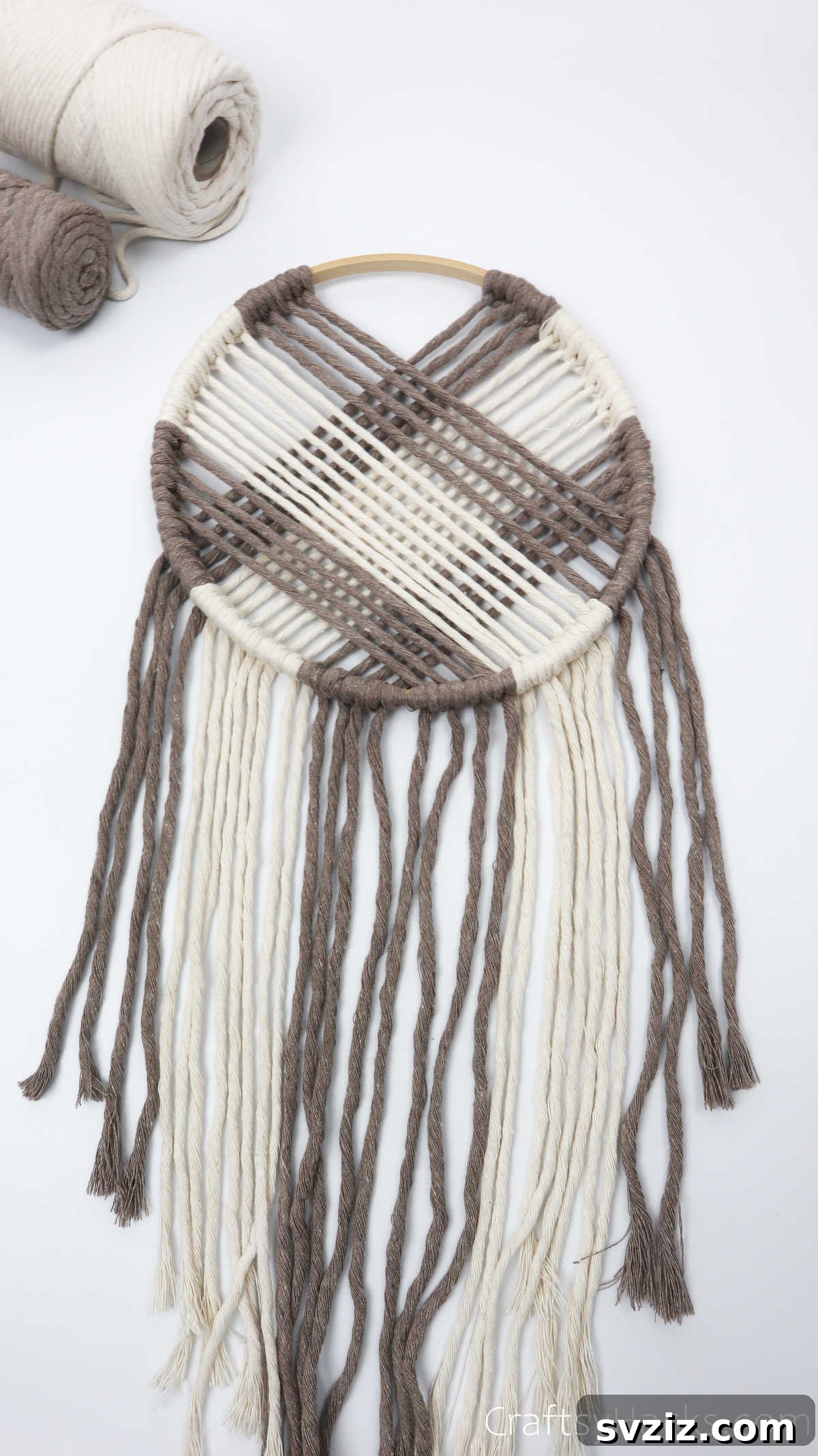 The completed dreamcatcher, lying flat, showcasing its full web and the arranged hanging cords.