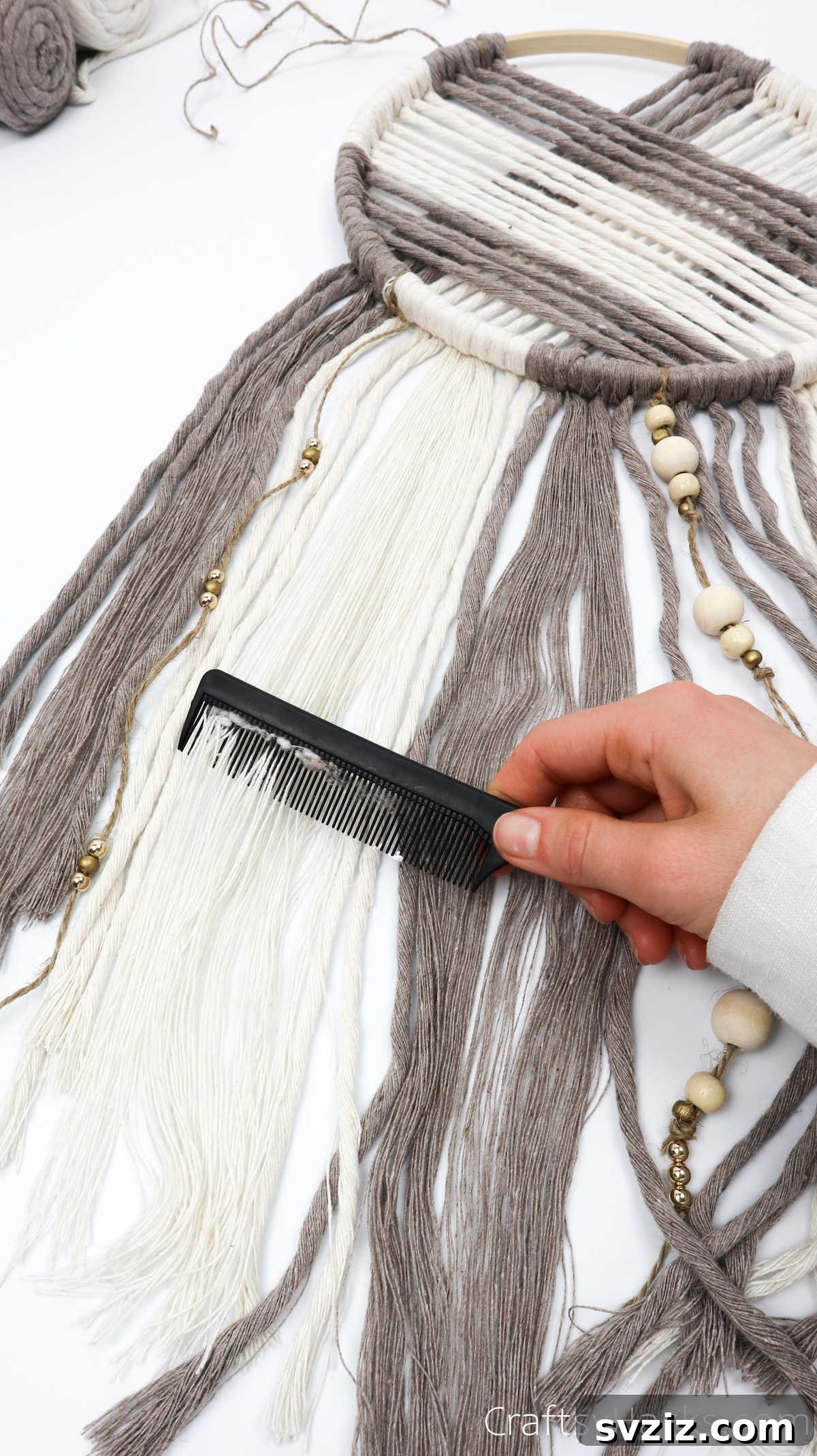 Combing out the ends of the yarn cords to create a smooth, feathered finish for the dreamcatcher.