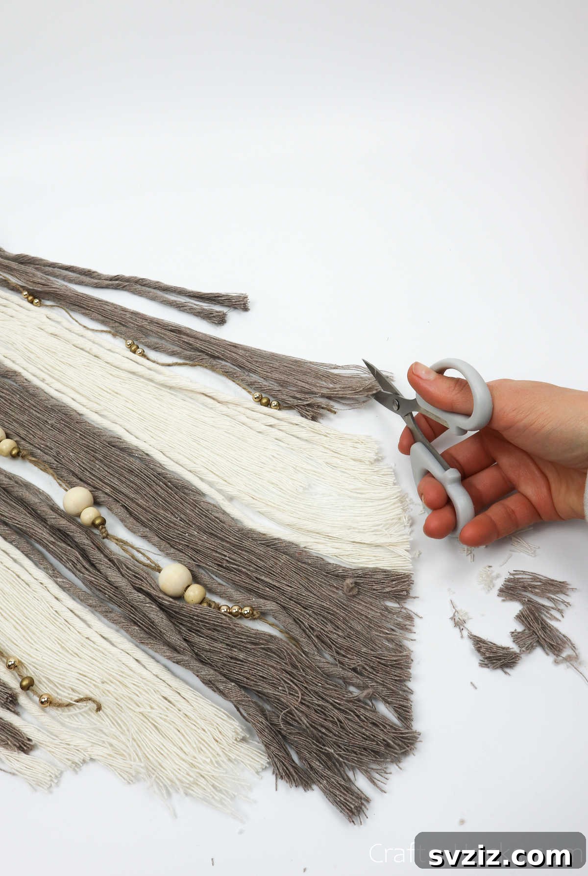 Cutting the ends of the yarn cords to create a tapered, aesthetic finish for the dreamcatcher.