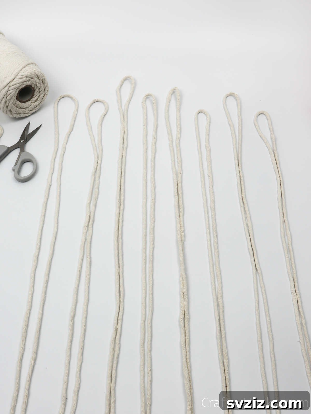 Eight lengths of cream-colored yarn, laid out neatly, ready to be incorporated into the dreamcatcher design.