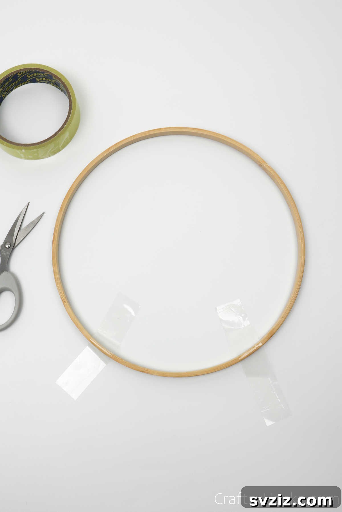 A wooden embroidery hoop secured to a surface with tape, providing stability for crafting.