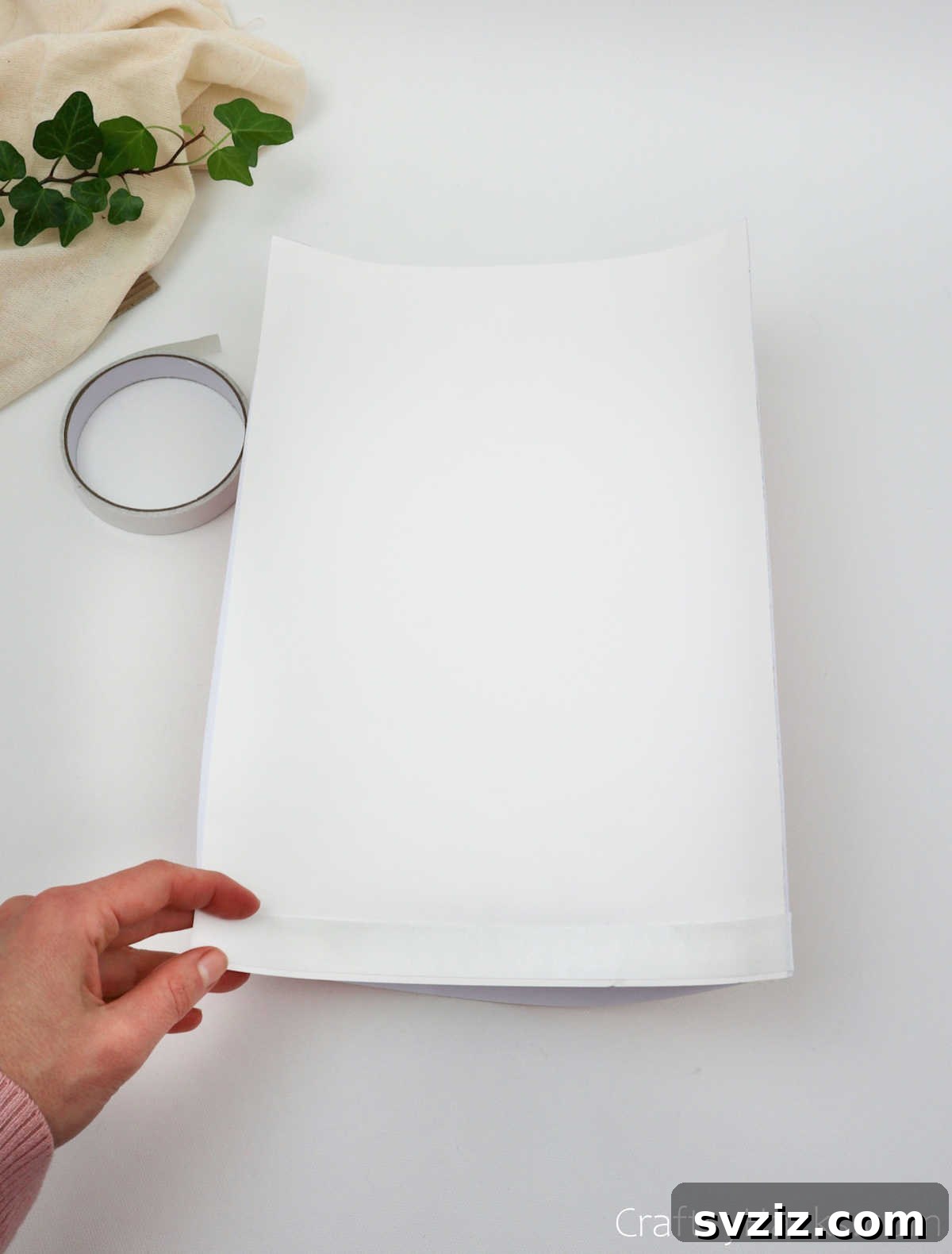 Craft Your Own Stunning Paper Lanterns 15 A strip of double-sided tape is applied along the side edge of the white paper, preparing for the final fold.