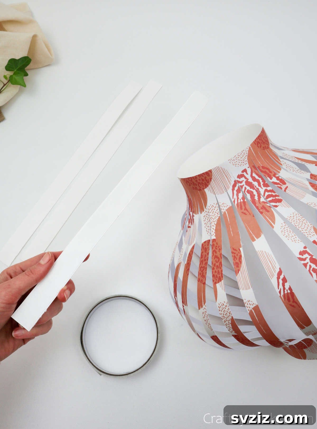 Craft Your Own Stunning Paper Lanterns 20 A hand holds a single white paper strip, ready to be used as trim or a handle for the DIY lantern.