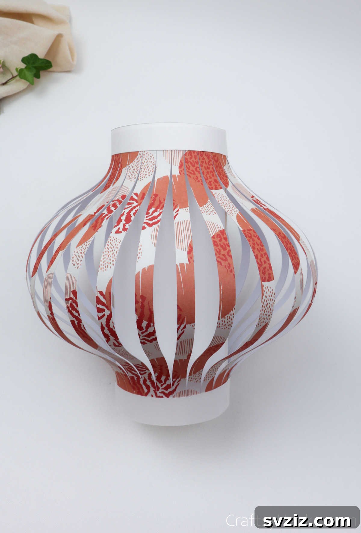Craft Your Own Stunning Paper Lanterns 21 A white paper strip is being carefully taped around the top edge of the paper lantern, creating a decorative trim.