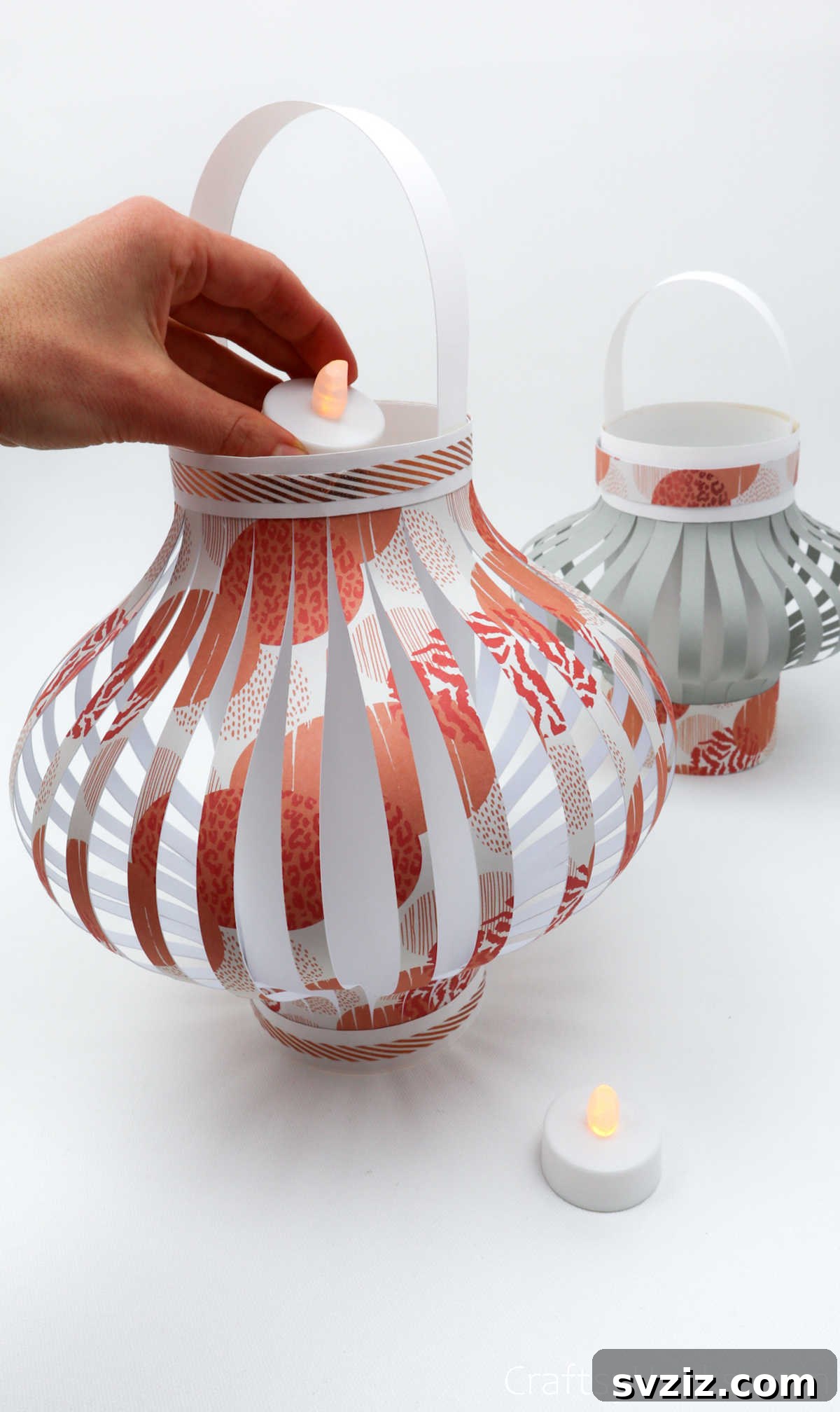 Craft Your Own Stunning Paper Lanterns 26 A hand gently places an electric tea light inside a finished paper lantern, ready to illuminate it with a soft glow.