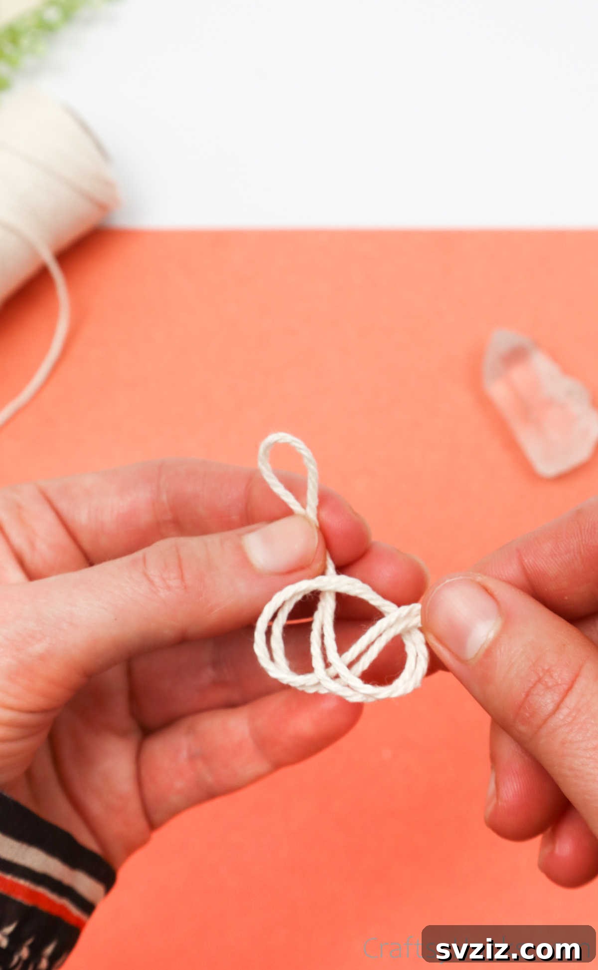 Simple Stone Necklace DIY Guide 13 Hands tying a simple overhand knot with two strands of cotton twine to secure the crystal's base