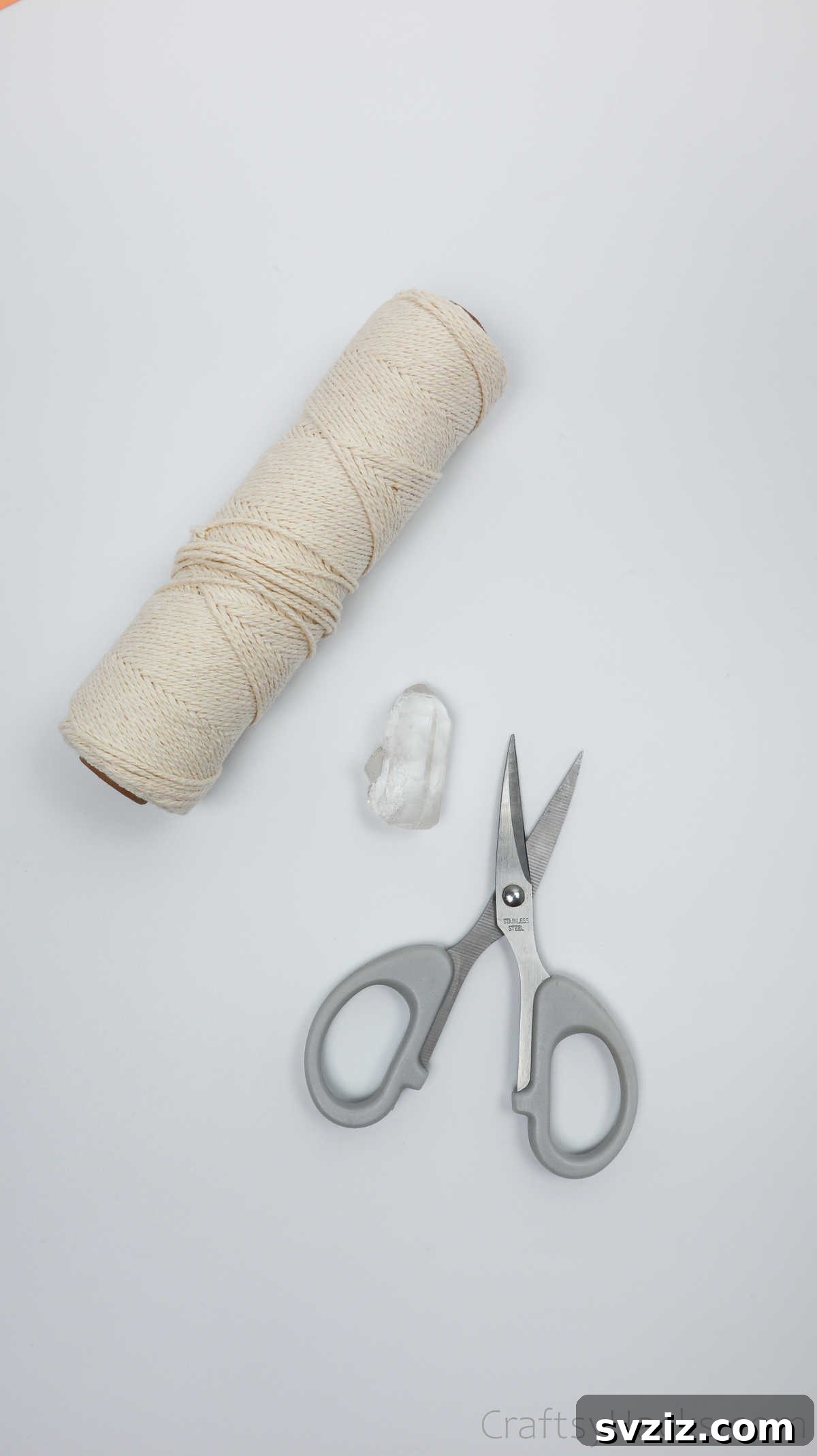 Simple Stone Necklace DIY Guide 5 Close-up of macrame craft supplies: a natural stone, a spool of cotton twine, and scissors