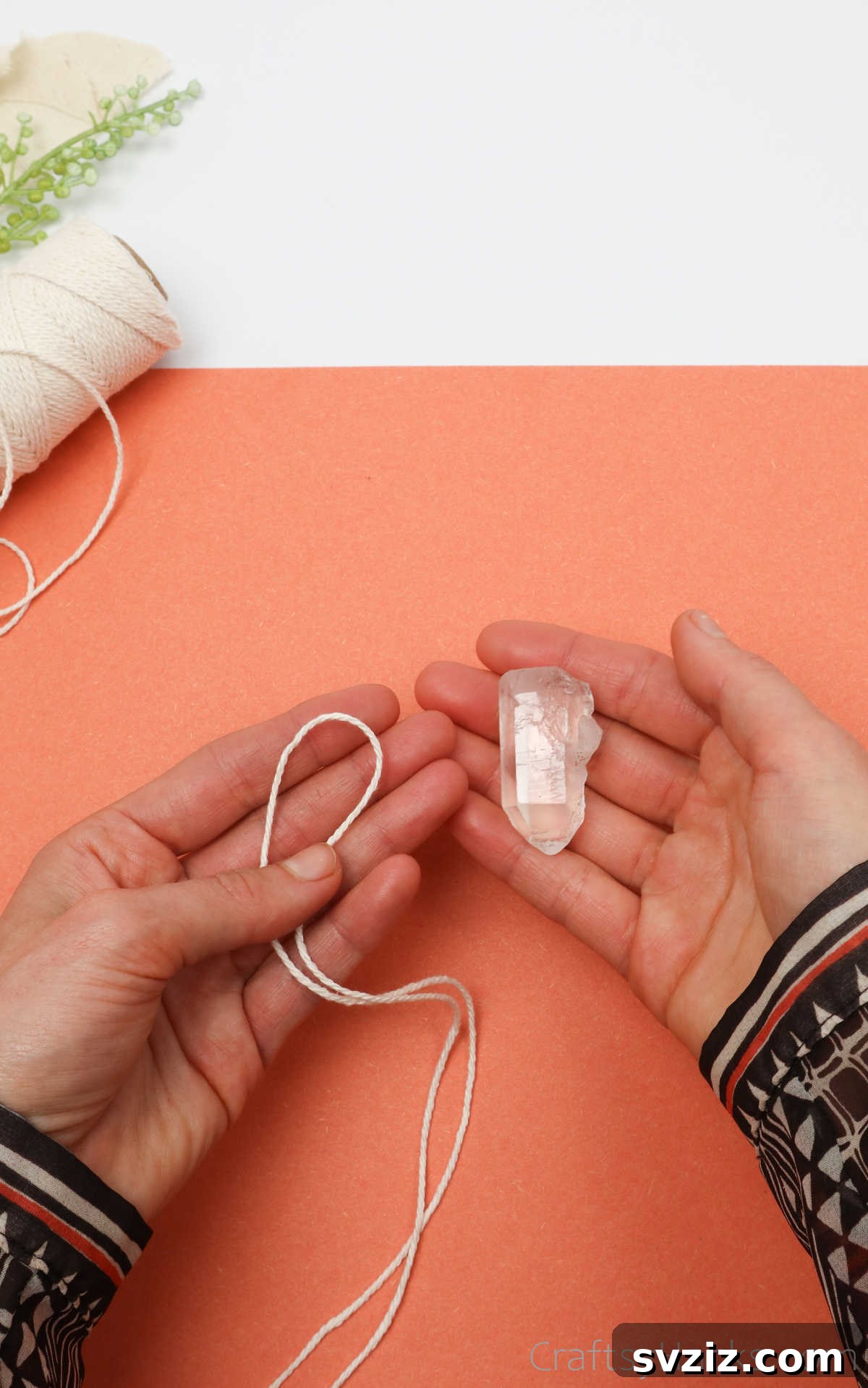 Simple Stone Necklace DIY Guide 9 Hands holding a crystal and a folded cord, with the cord being looped around the base of the crystal