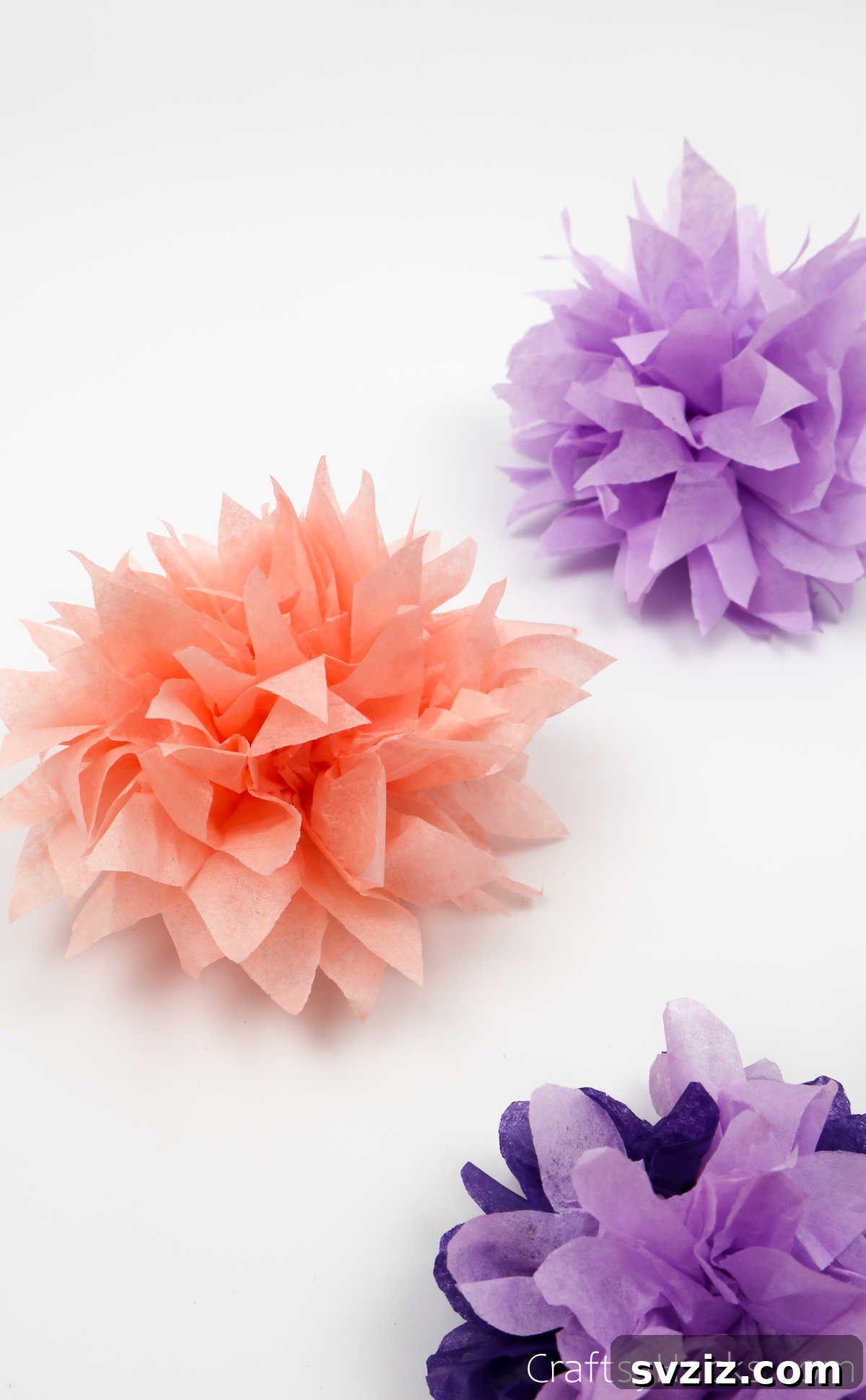 Three beautifully crafted tissue paper flowers in pastel shades, perfect for adding a handmade touch to any space