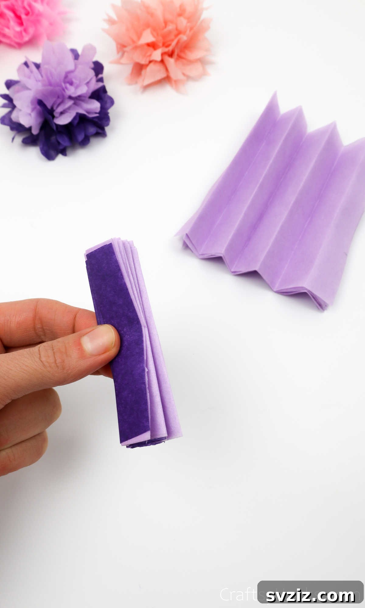 A neatly folded stack of tissue paper, prepared in an accordion style, ready for the next step of flower making
