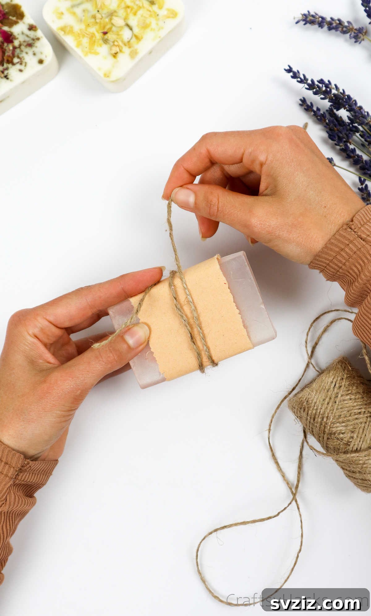 Your Guide to Crafting Homemade Soap 27 Tying jute twine around a craft-paper-wrapped soap bar