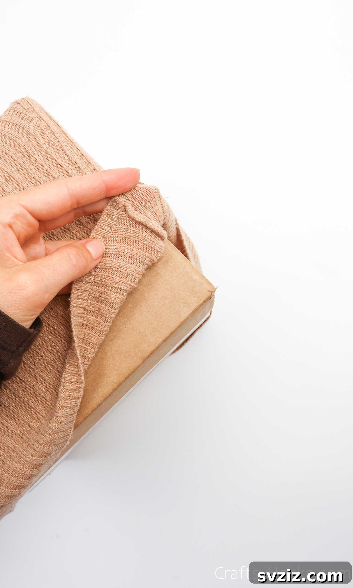 Close-up of a hand holding the corner of the box with sweater fabric