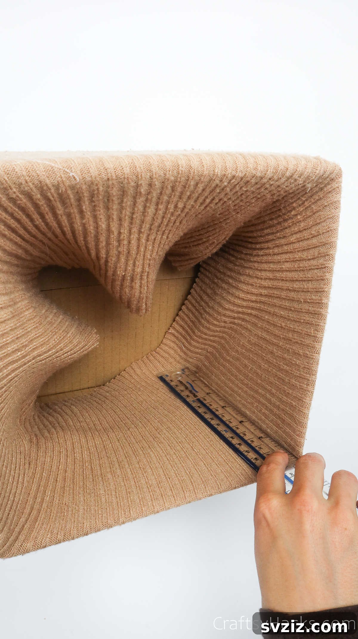 Using a ruler to flatten sweater fabric inside the box