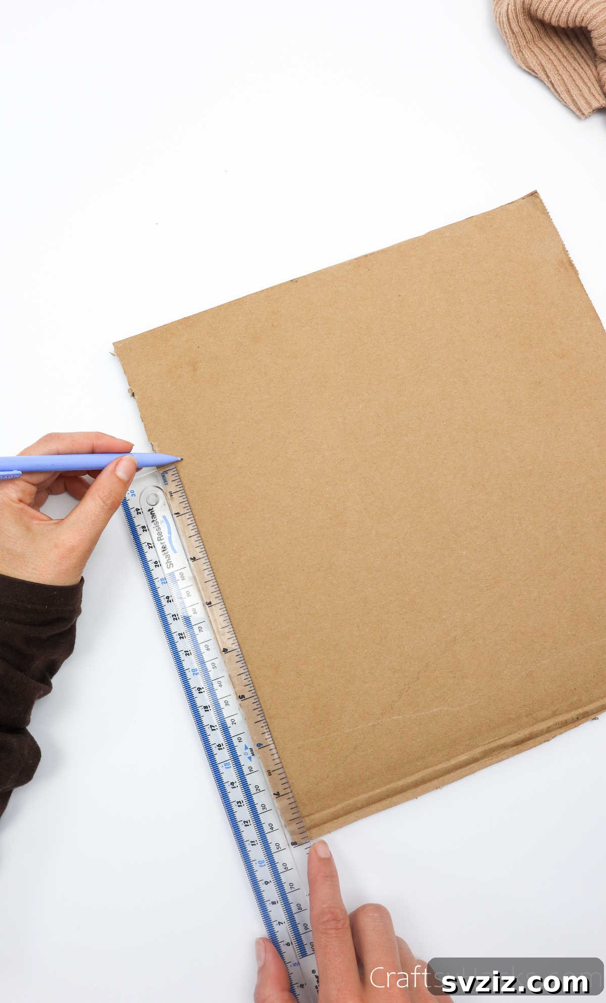 Measuring a side of the cardboard for the base