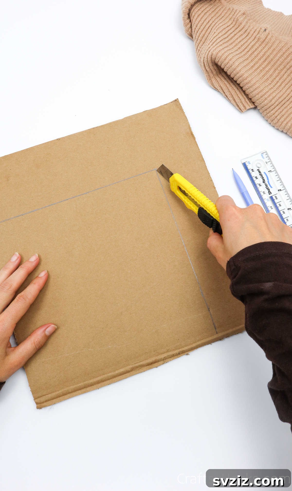 Cutting the measured cardboard piece with a box cutter