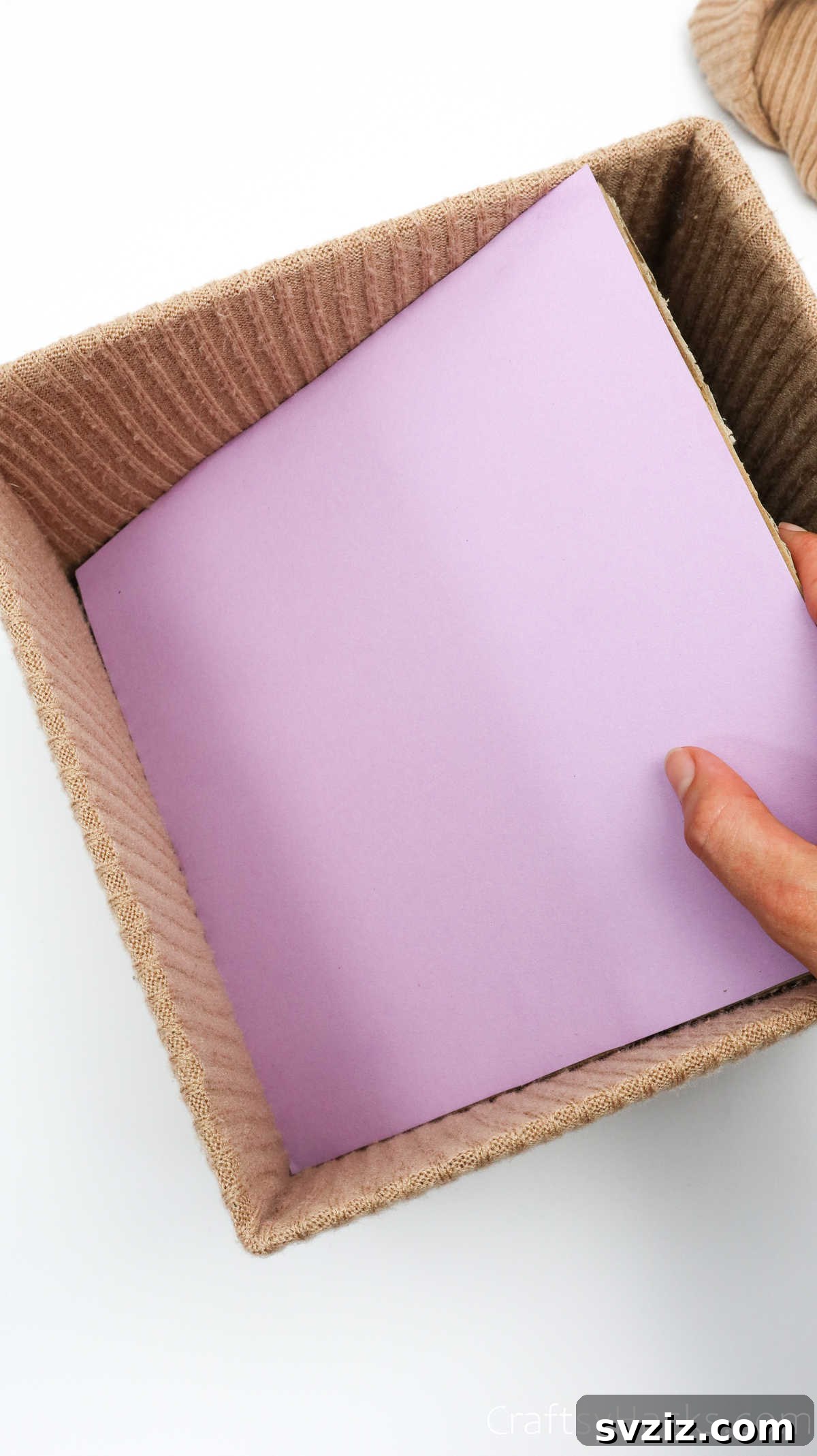 Inserting the covered cardboard base into the box