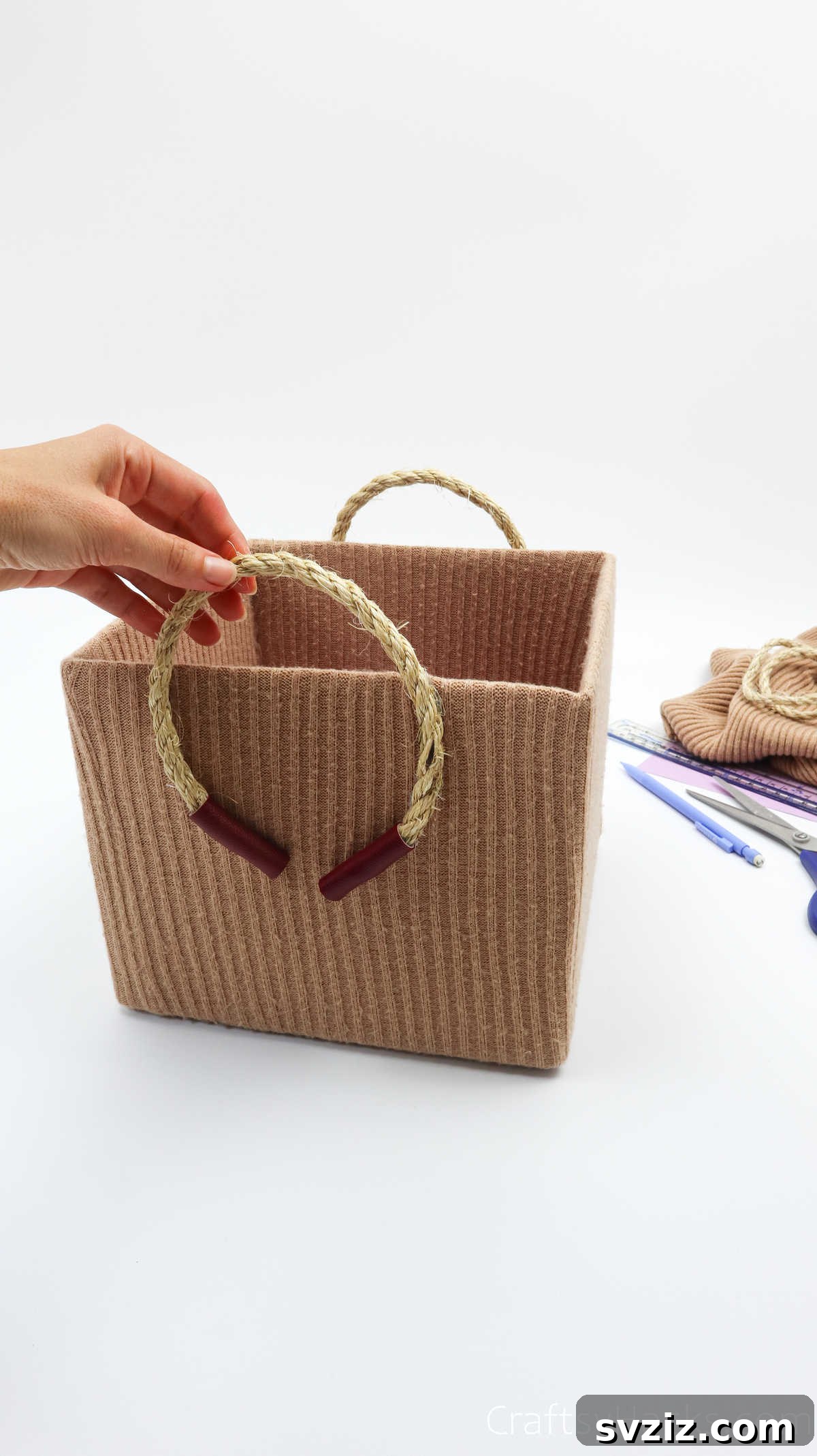 Hand holding the rope handle of a finished storage box