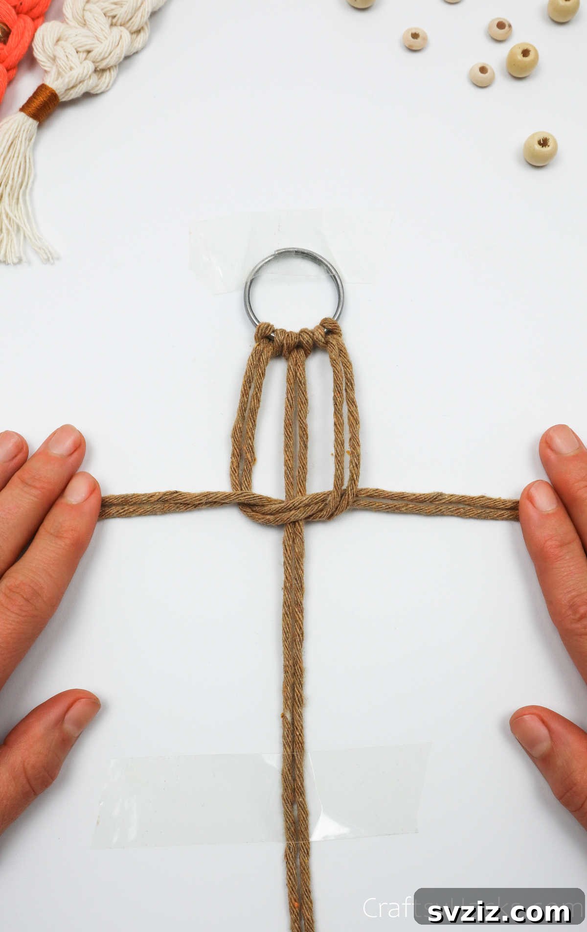 The first half of the square knot is tightened, pulling the cord ends in opposite directions.