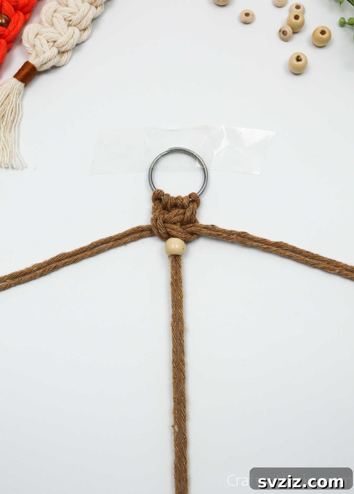A decorative bead threaded onto the middle macrame cords, placed below the first square knot.