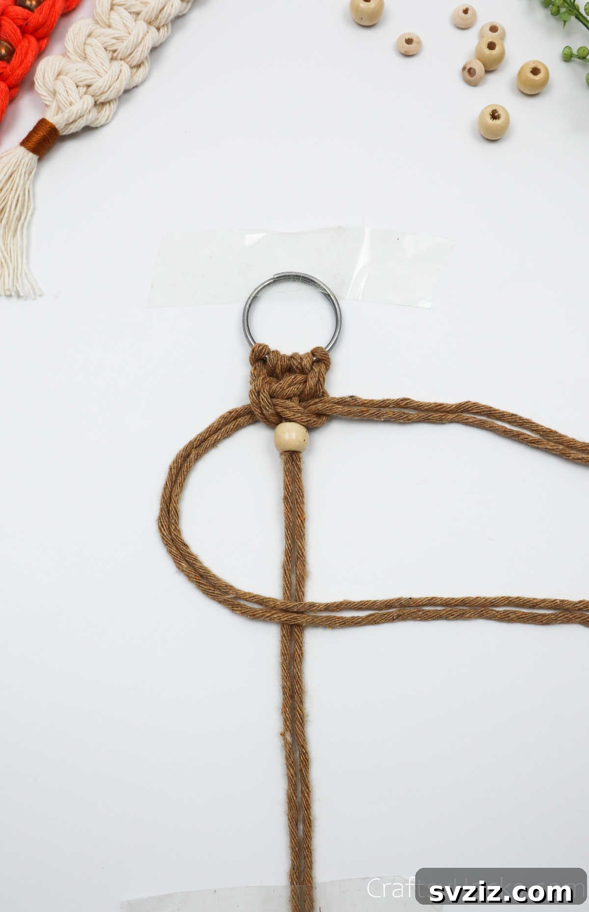 Starting the first half of a new square knot below the bead to secure it.