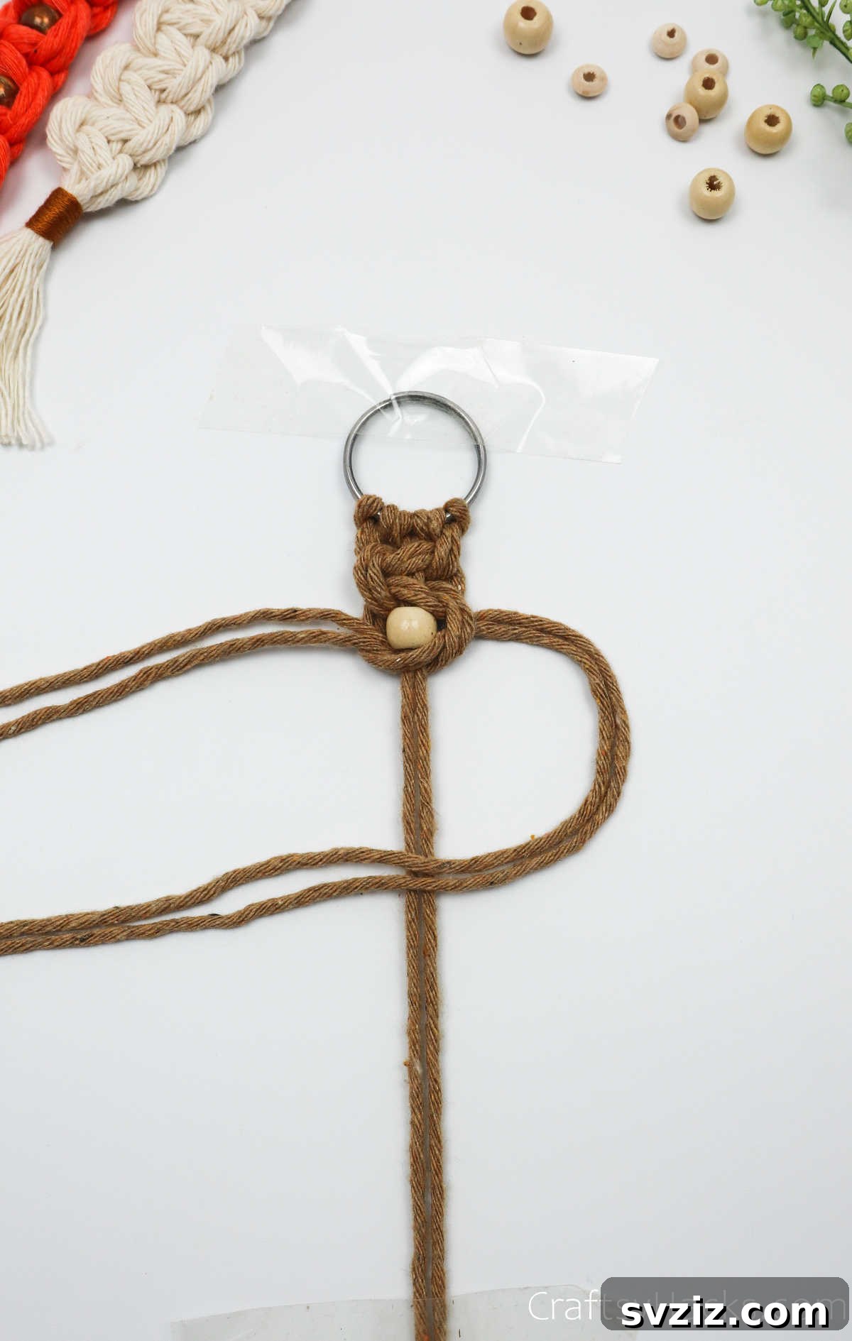 Completing the second half of the square knot to secure the bead in the macrame keychain.