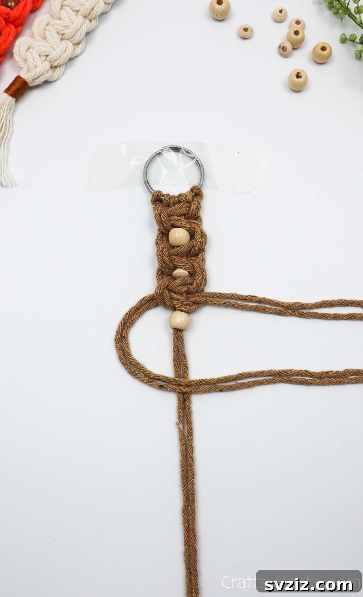 Adding another bead to the macrame keychain, continuing the pattern.