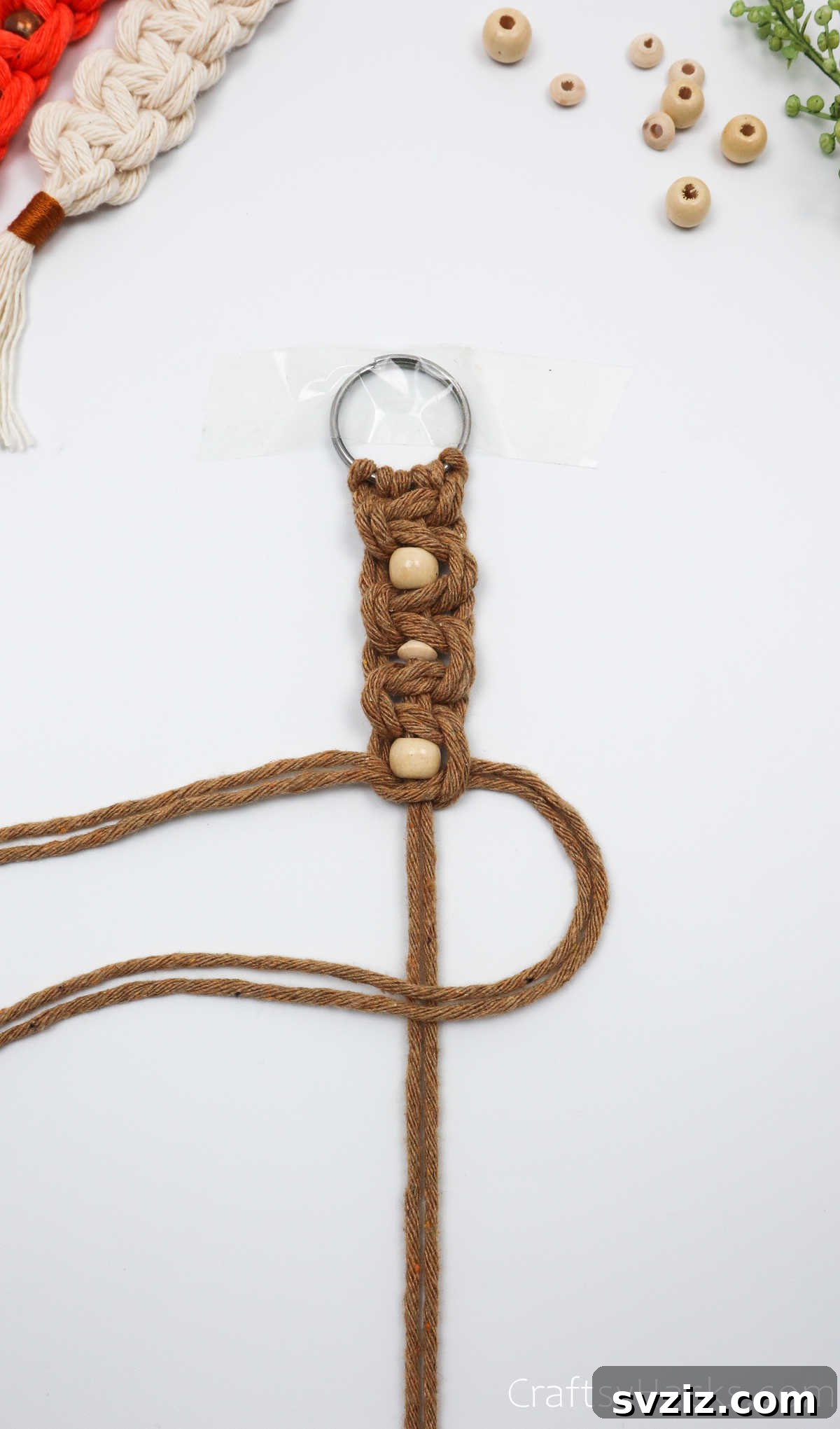 Tying a square knot below the newly added bead to secure it.