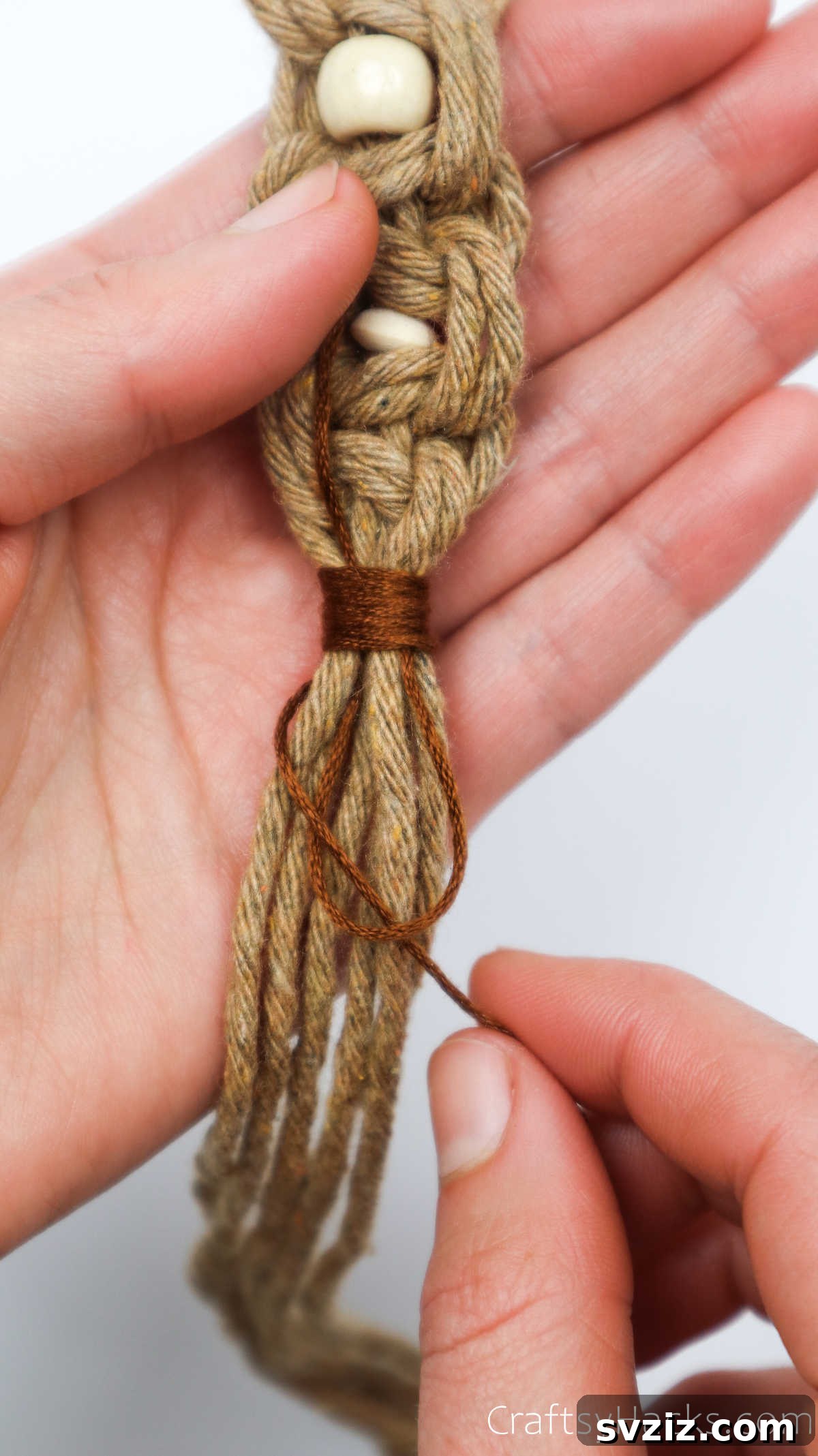 The two ends of the embroidery thread are pulled to tighten the finishing wrap knot.