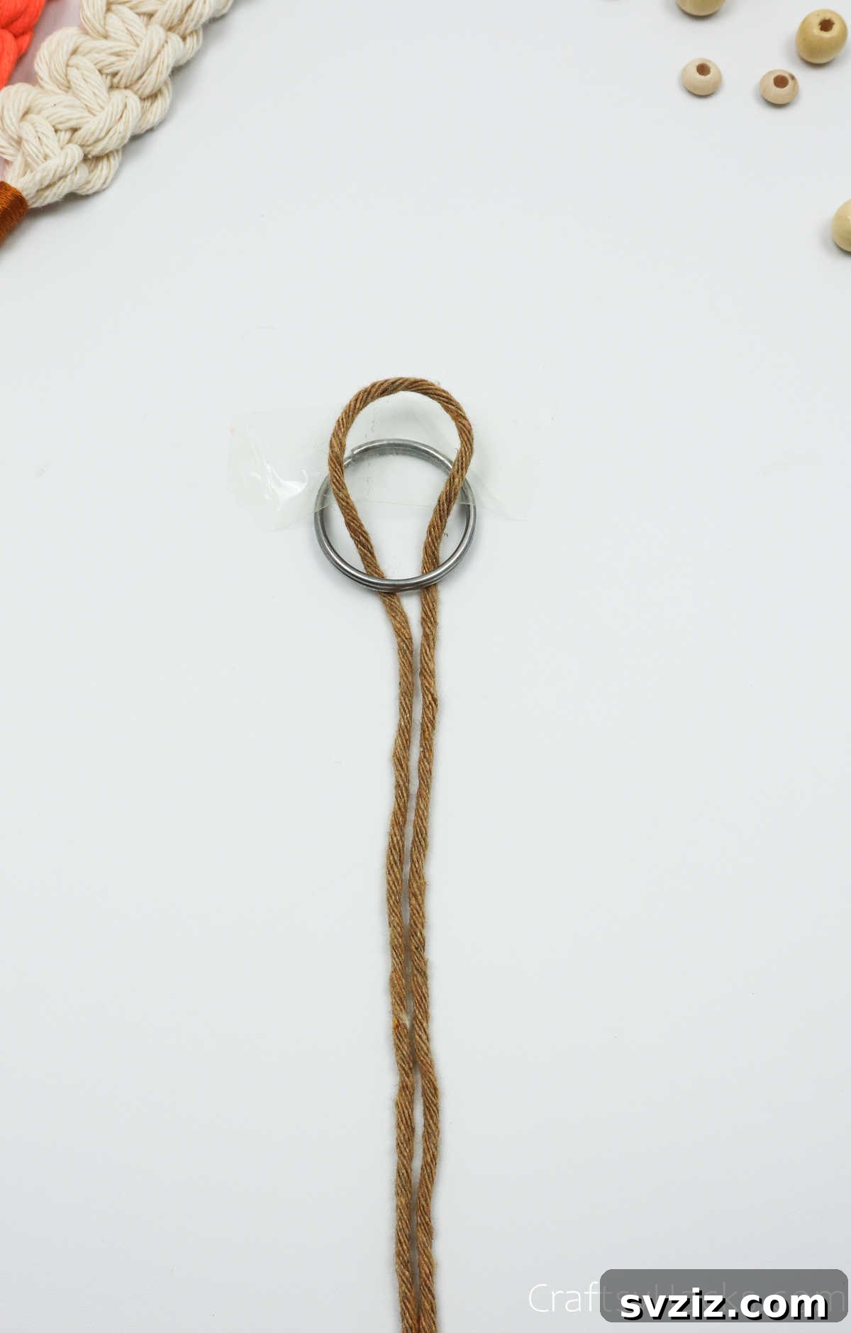 The macrame cord being looped under and through the key ring to start a lark's head knot.
