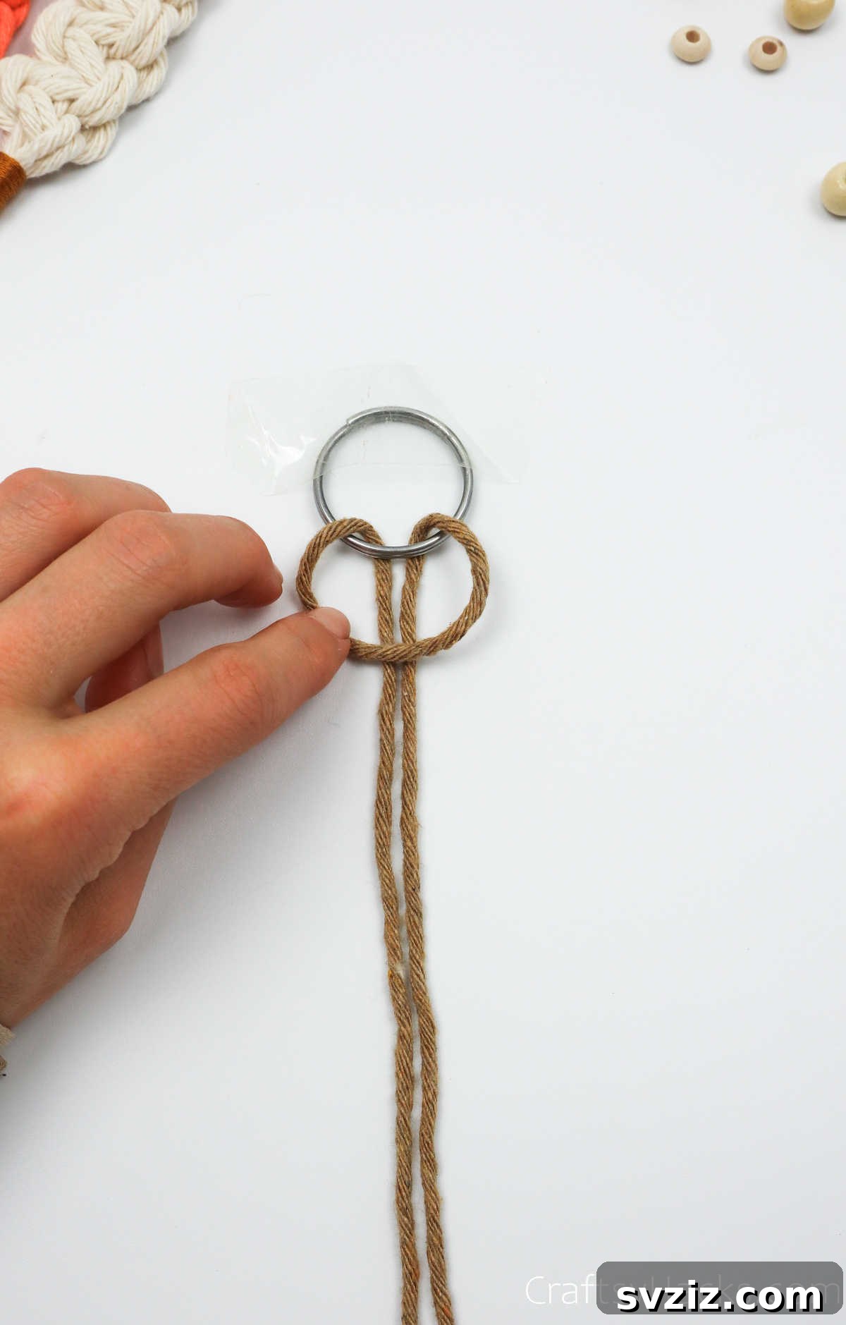 Close-up of the macrame cord being pulled through the loop to form a lark's head knot.