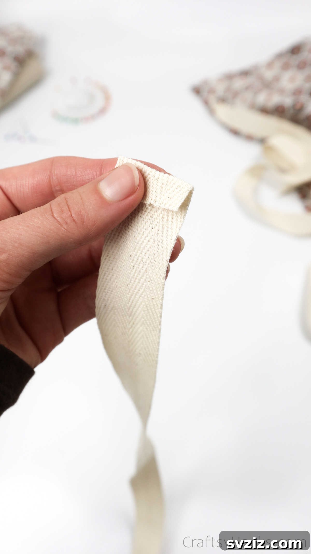Craft Your Own Custom Apron 29 A neatly folded ribbon edge, secured with a pin, ready to be attached as a durable strap for the DIY apron.