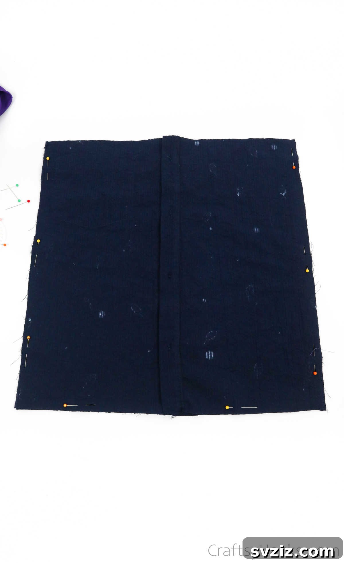 Pinning the edges of two shirt fabric pieces together, securing them for sewing the tote bag