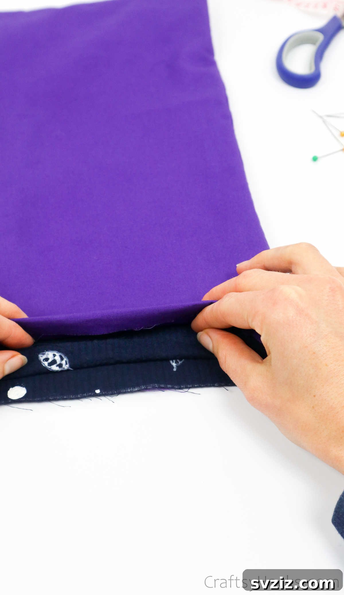 Folding fabric edge for a clean finish, a detailed step in crafting the DIY tote bag